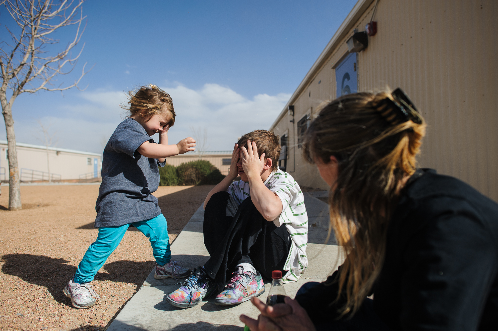  Vinny, age 13, plays a game with his sister, Elycia, age 4, outside the counseling office where he will be evaluated for post traumatic stress, 2012. 