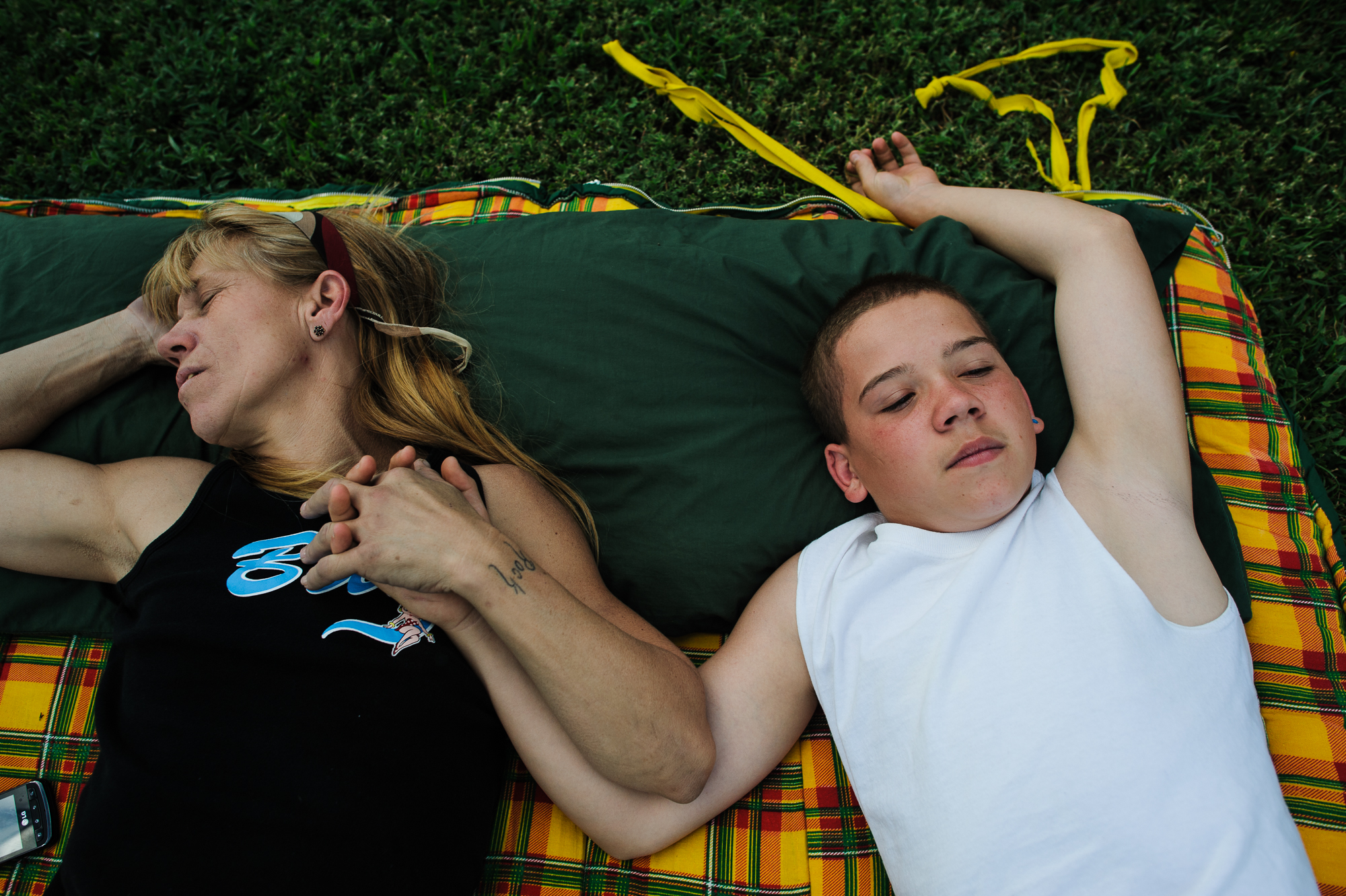  Vinny, age 13, lies on a blanket with his mom, Eve, as she sleeps in the backyard of his aunt’s home during an organized family visit, 2012. 