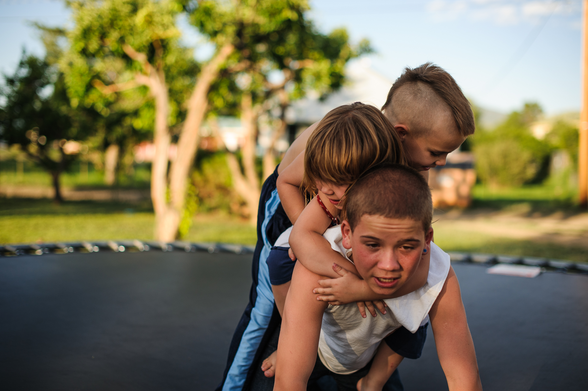  Vinny, age 13, carries his sister and brother on his back on a trampoline at his aunt’s home during an organized family visit, 2012. 