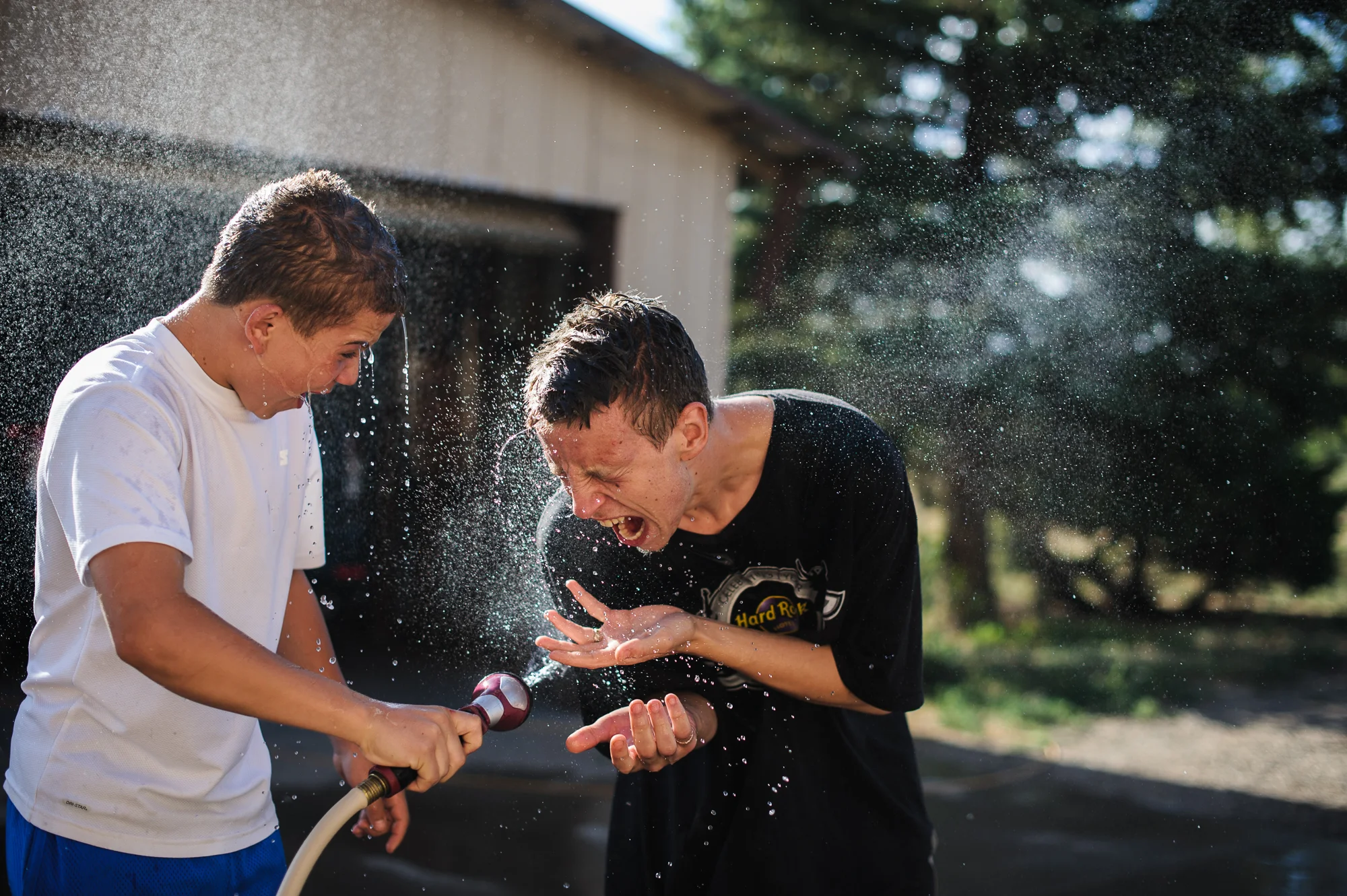 Vinny, age 13, sprays David, age 19, with a hose, 2012.
