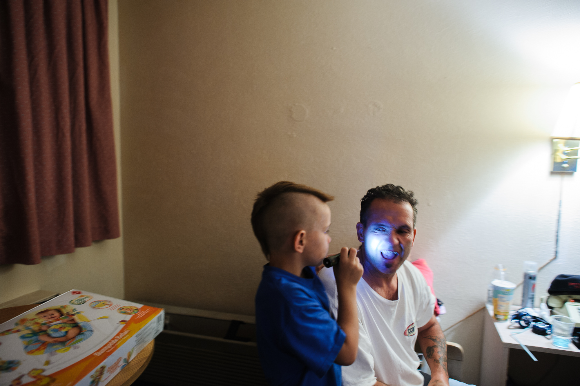  Michael, age 7, points a flash light at his dad, Eddie’s, face during a family visit inside David’s motel room, 2012. 