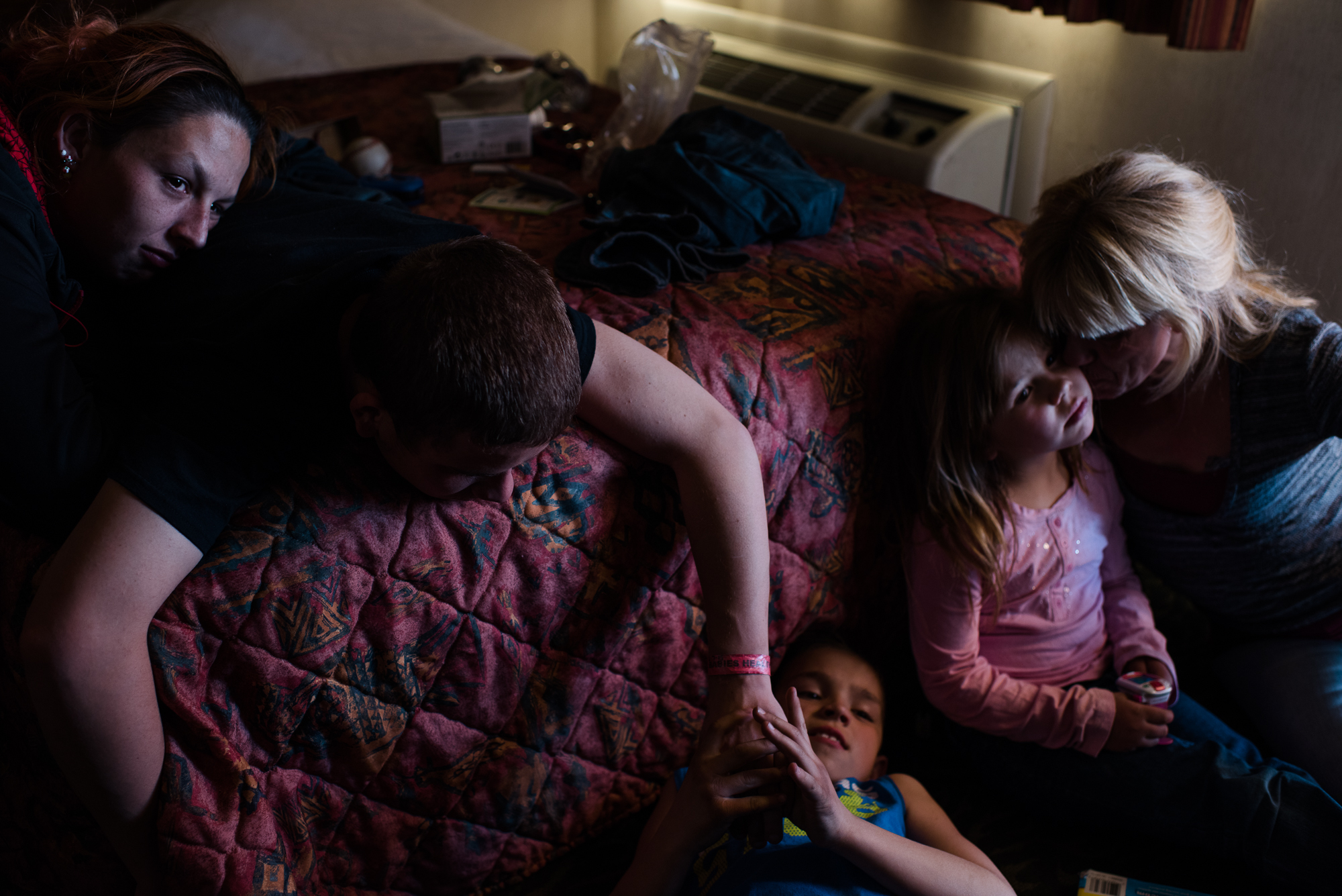  Vinny, age 16, tickles Michael, age 10, while Krystle rests her head on Vinny’s back; Eve sits with Elycia on the right side of the bed during a visit at Eddie’s motel room where Elycia and Michael live, 2015. 