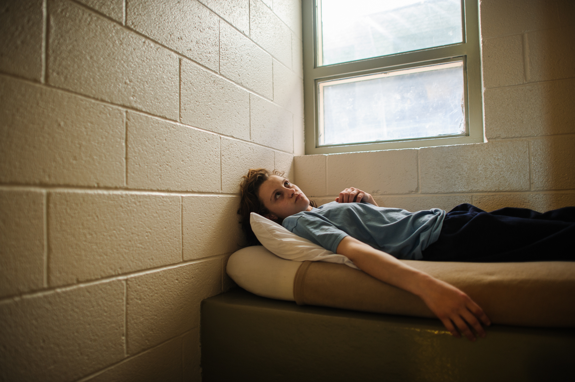  Alysia, age 16, lies on her bed in her cell at the juvenile detention center.  