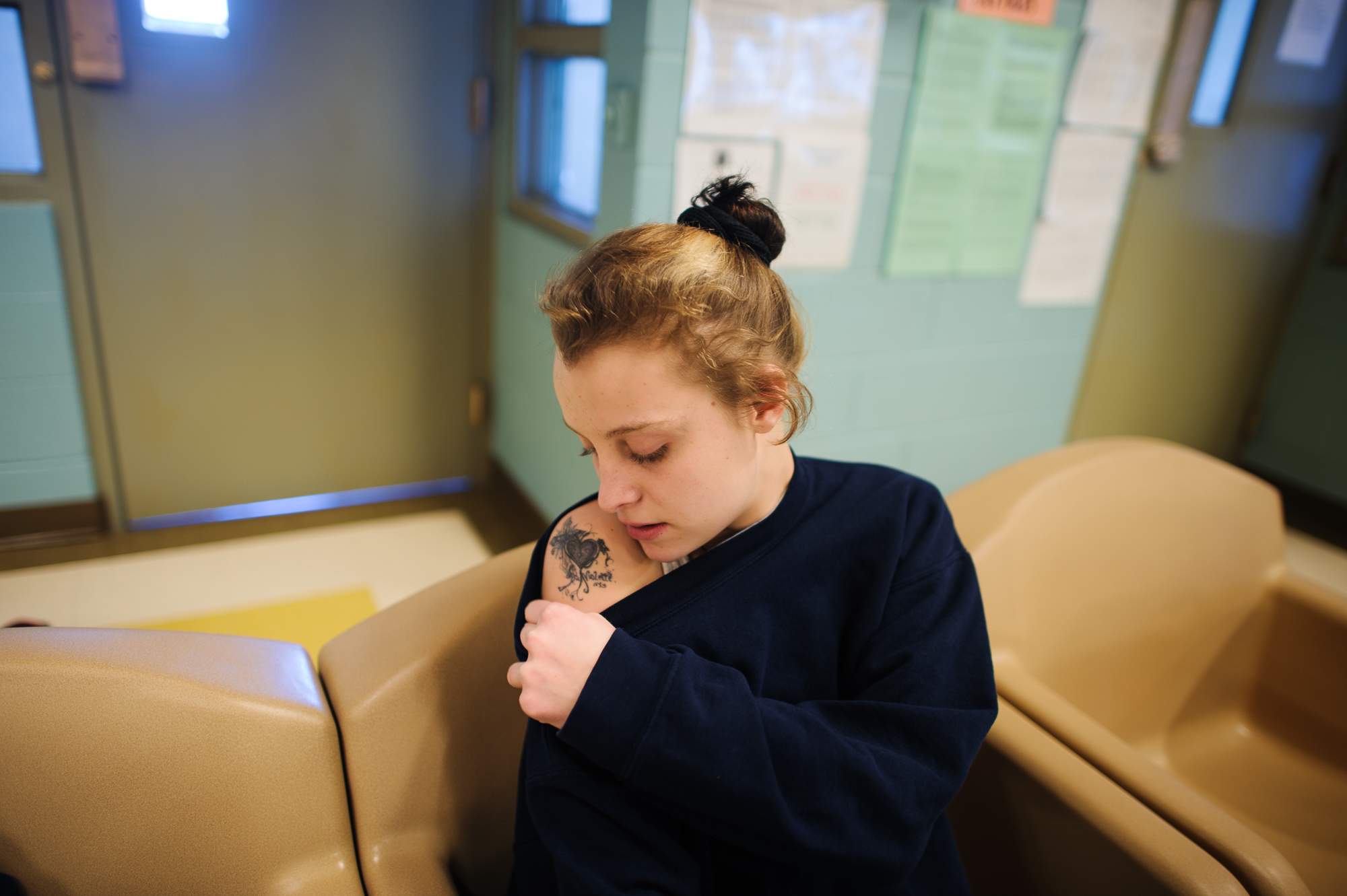  Alysia, age 16, looks at her tattoo, as she sits in the communal area at the juvenile detention center.  