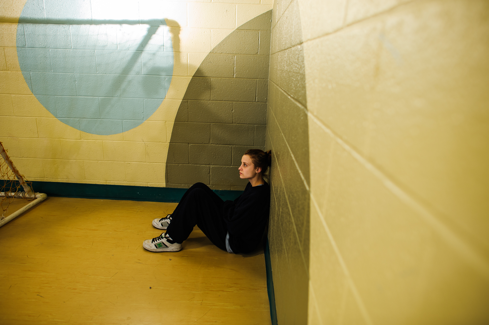  Alysia, age 16, sits inside the gym, as other girls play handball and basketball.  