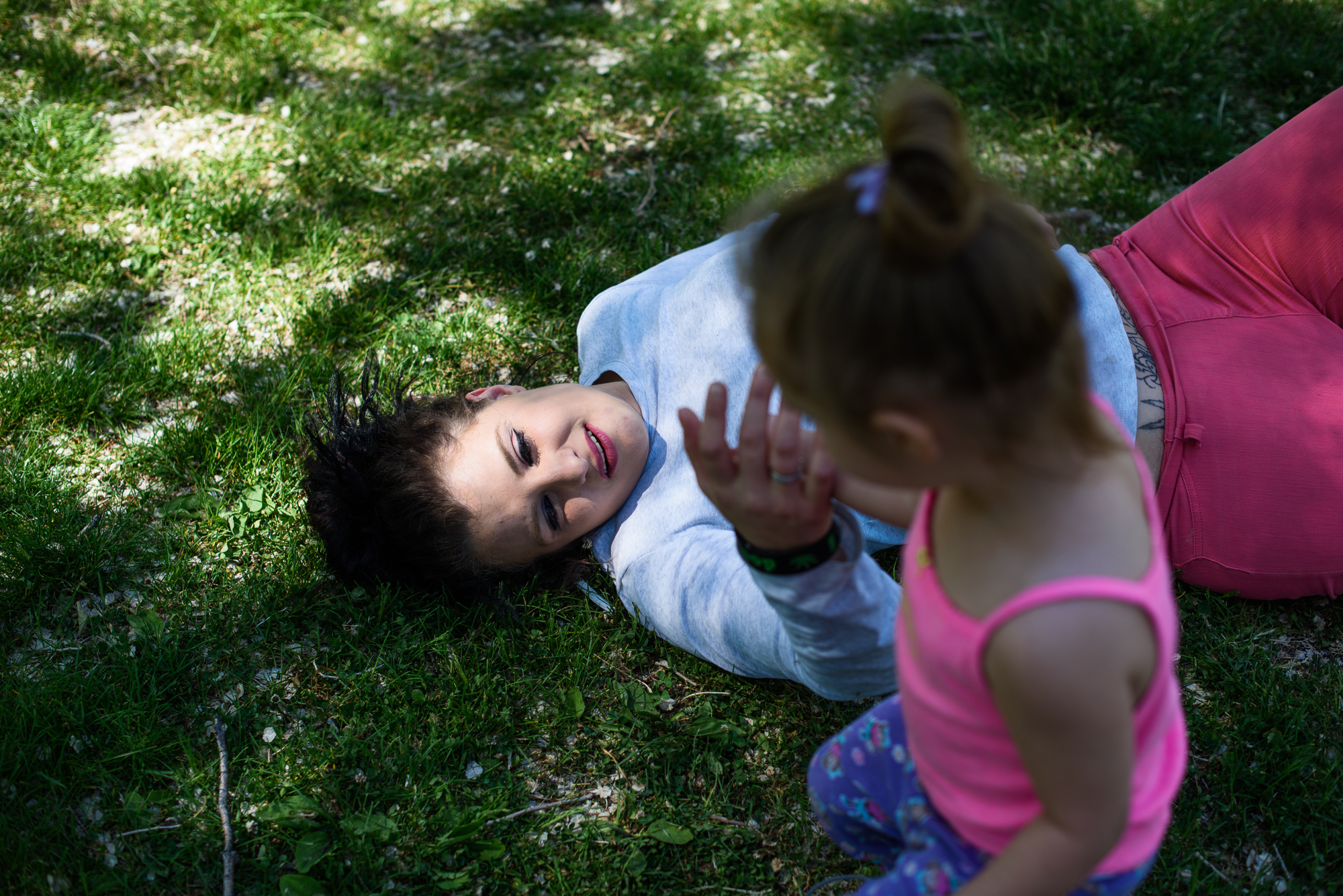  Alysia lies on grass at the park as Leticia touches her hand. “I try to give her what I did not have. Take her out. Make childhood something fun and innocent,” says Alysia. 