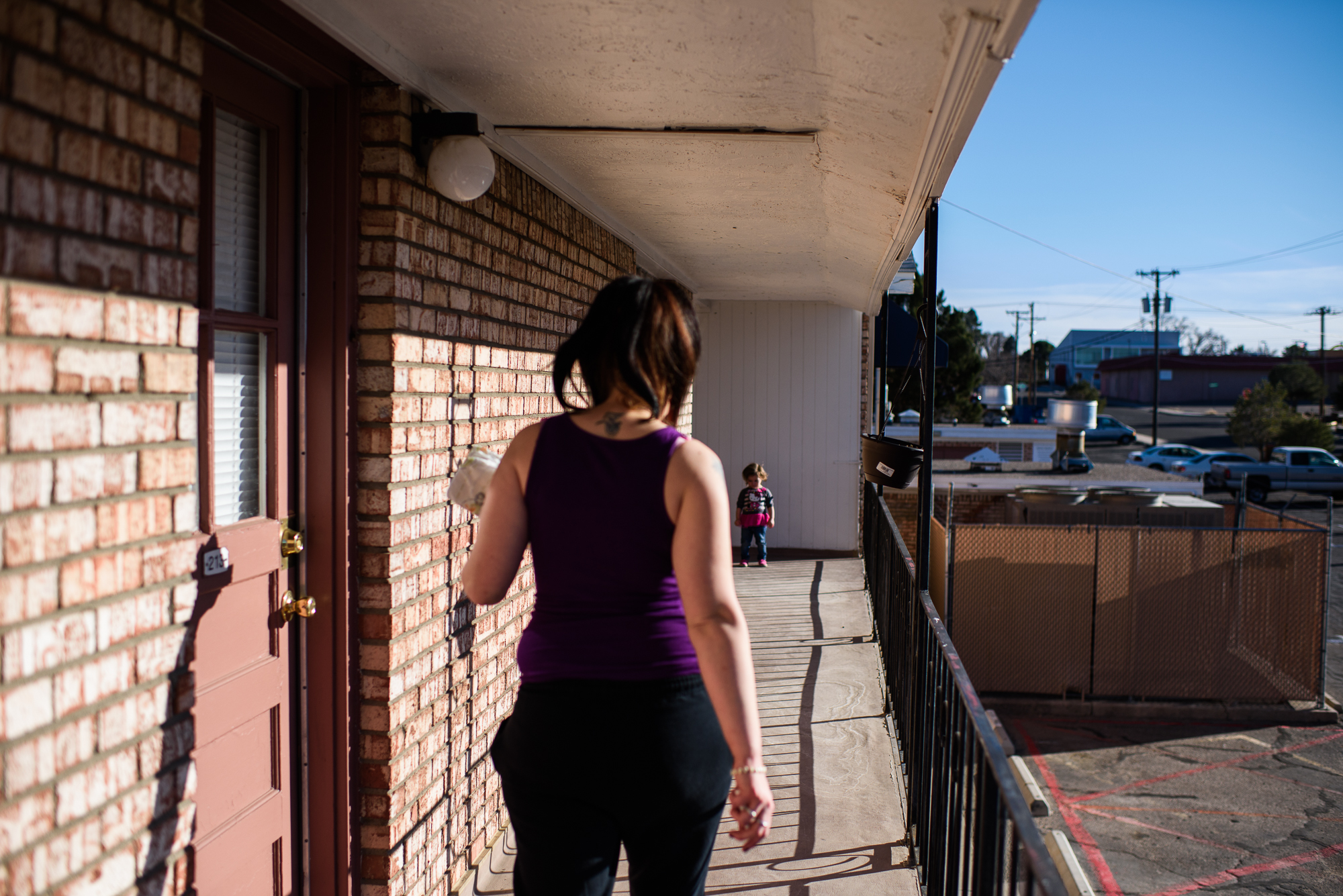  Leticia, age 2, waits for Alysia, age 20, at the end of the corridor, as Alysia walks towards her at their apartment complex.  