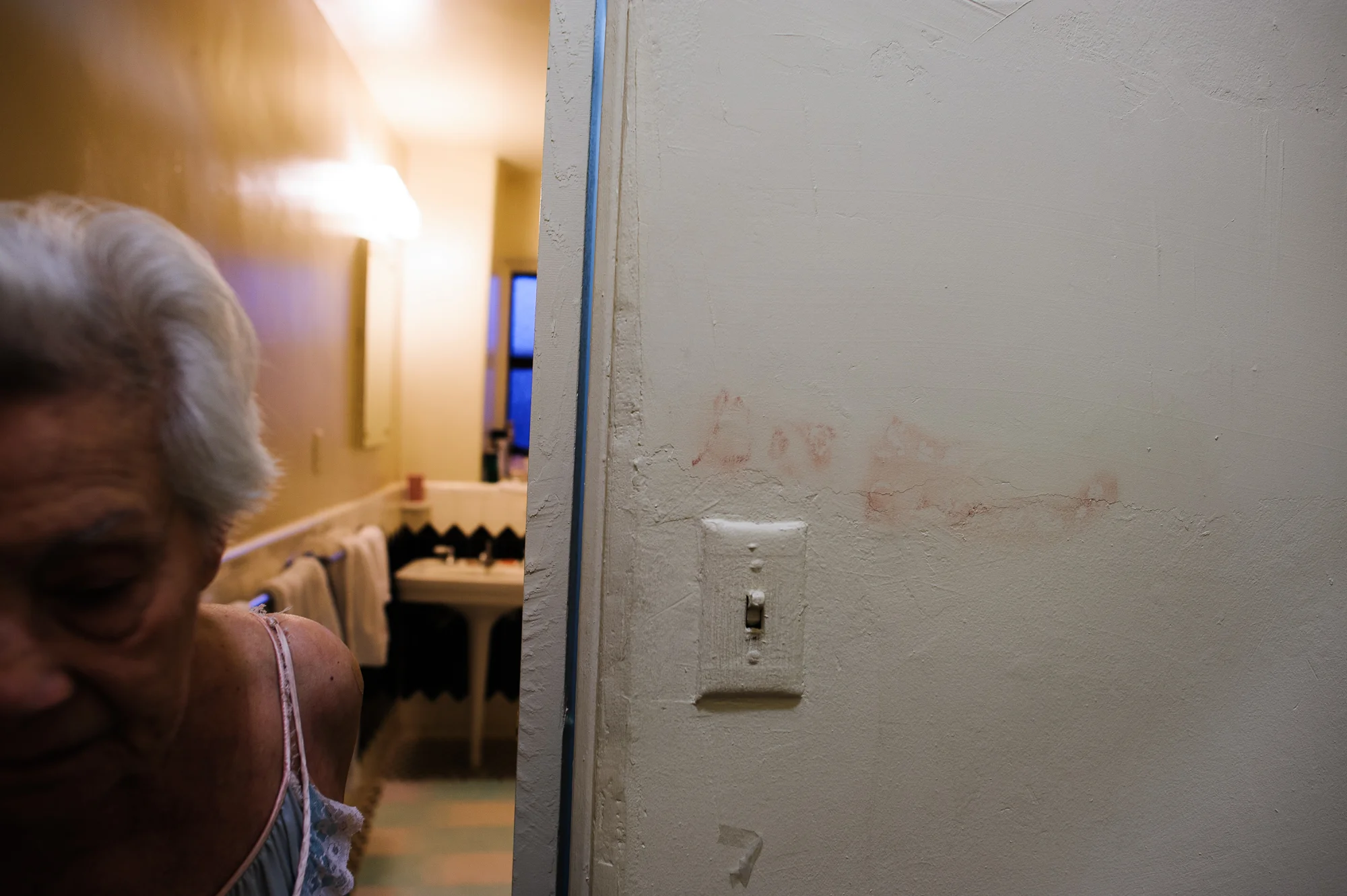 Bianca, age 85, walks passed words she wrote on her wall in lipstick, 2010.