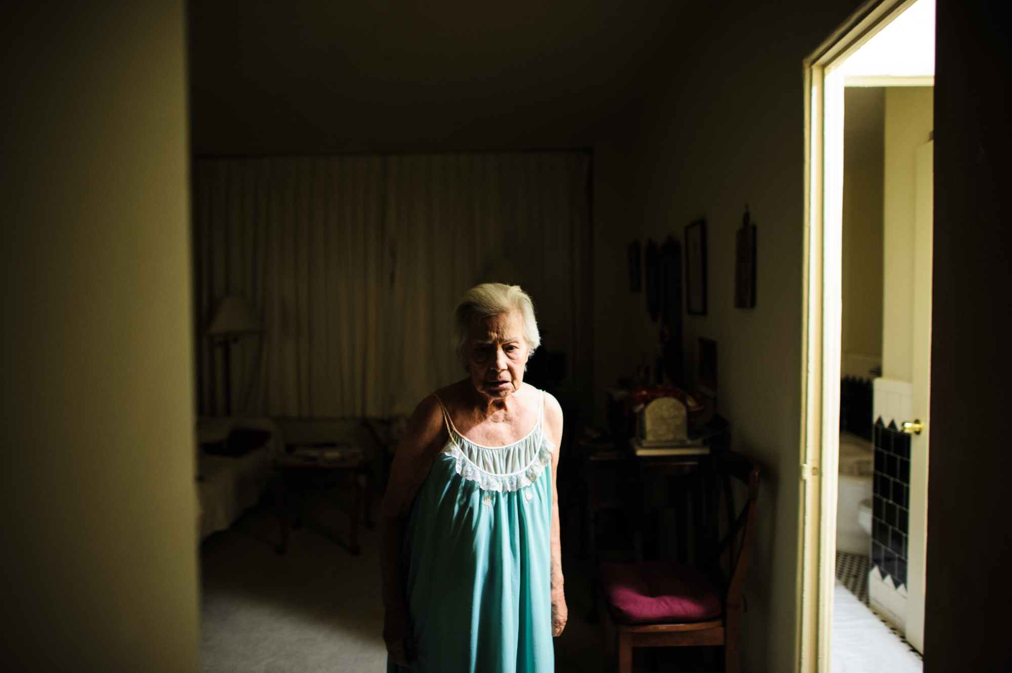  Bianca, age 86, stands her apartment at night, looking at the front door in fear that someone will come in, 2011.  