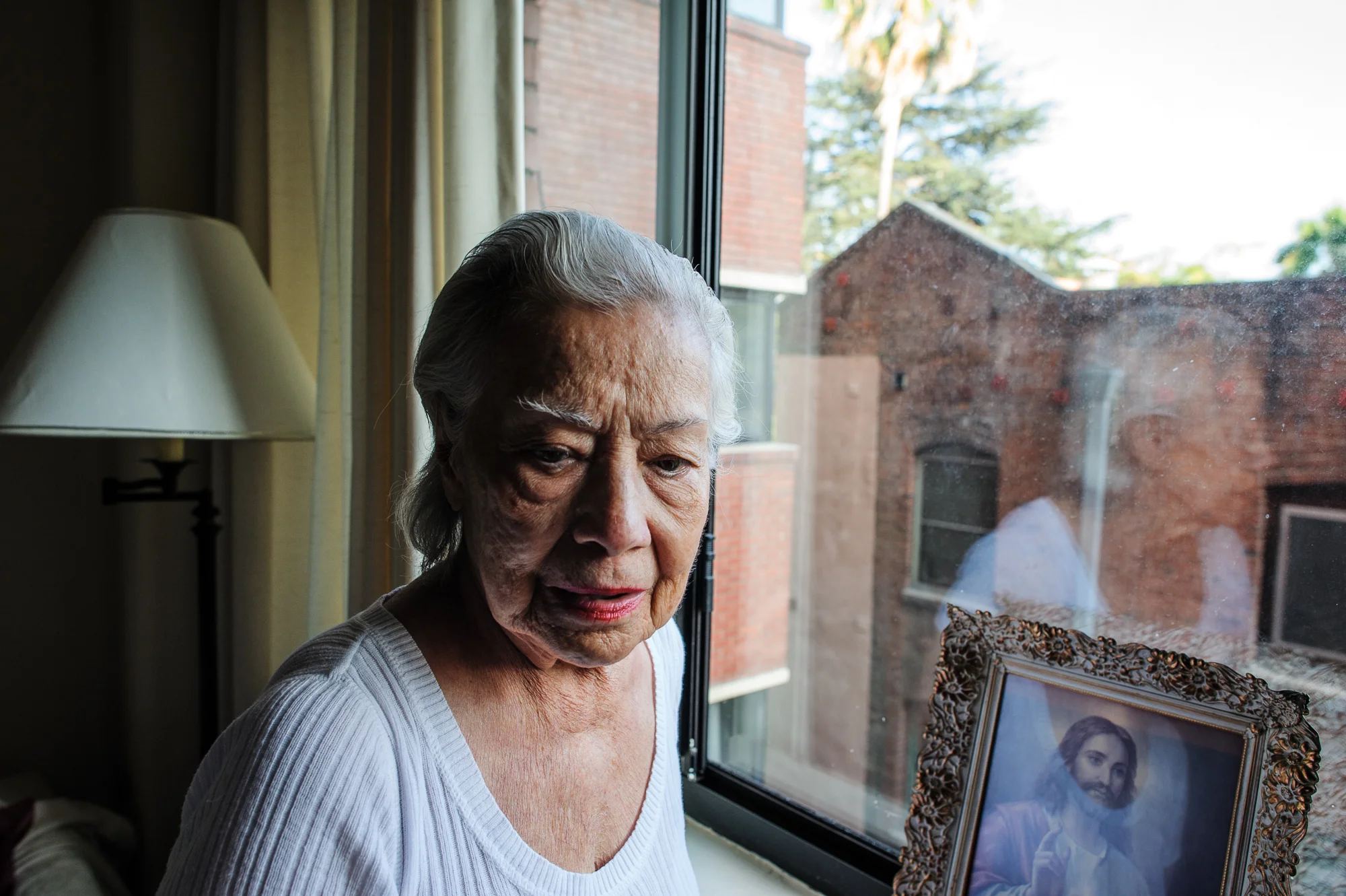 Bianca, age 85, stands by her window in the afternoon, 2010.
