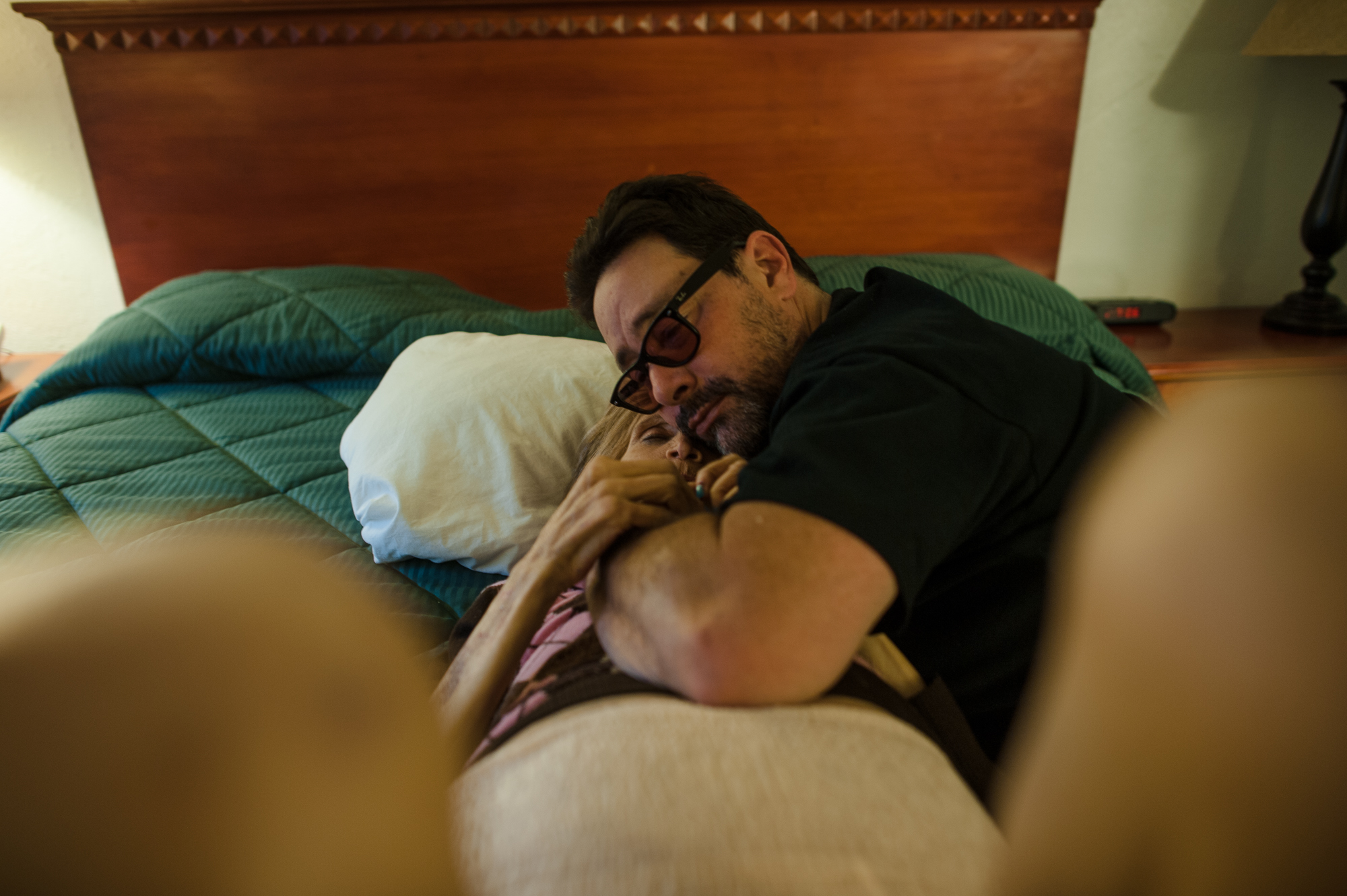  Rosie and Adam embrace on the bed at the motel where they are staying during a vacation to Palm Springs, California.  