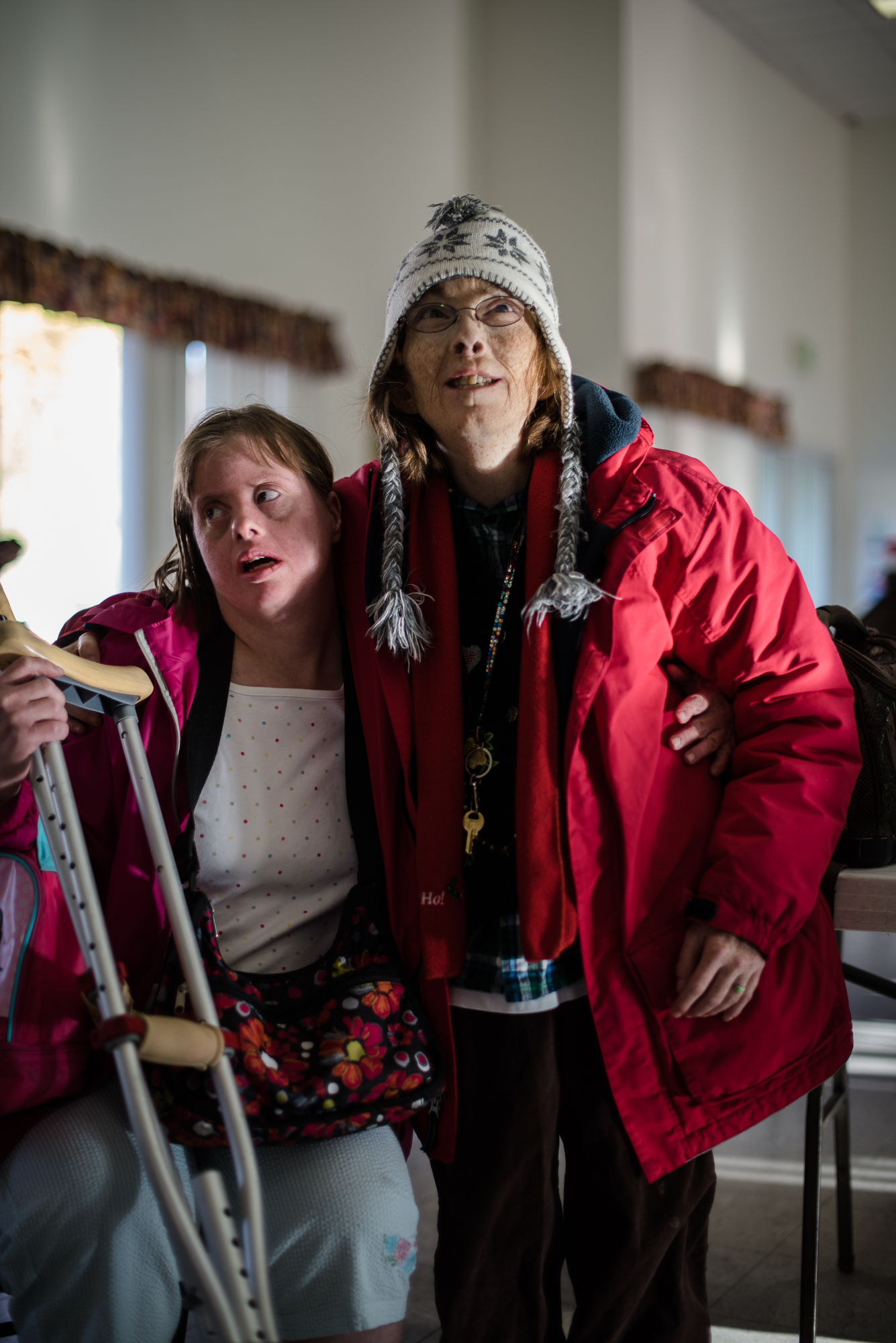  Krysta sits next to her friend, Sandra, who stands, waiting for the residents to be allowed back to their homes after the daily workshop.  