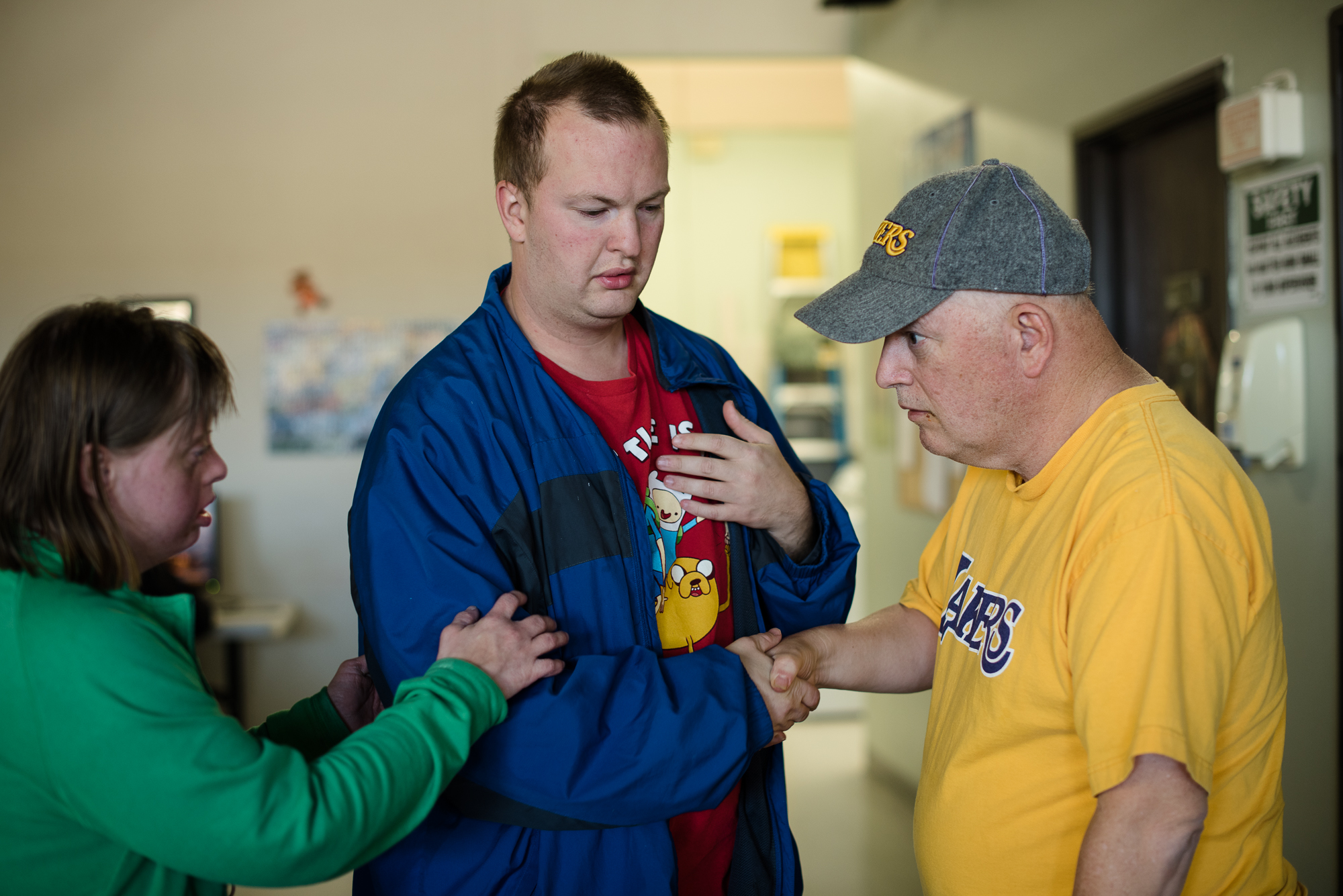 Nathaniel shakes hands with Gary, a participant of the workshop, after an argument, while Krysta holds Nathaniel’s arm in support.