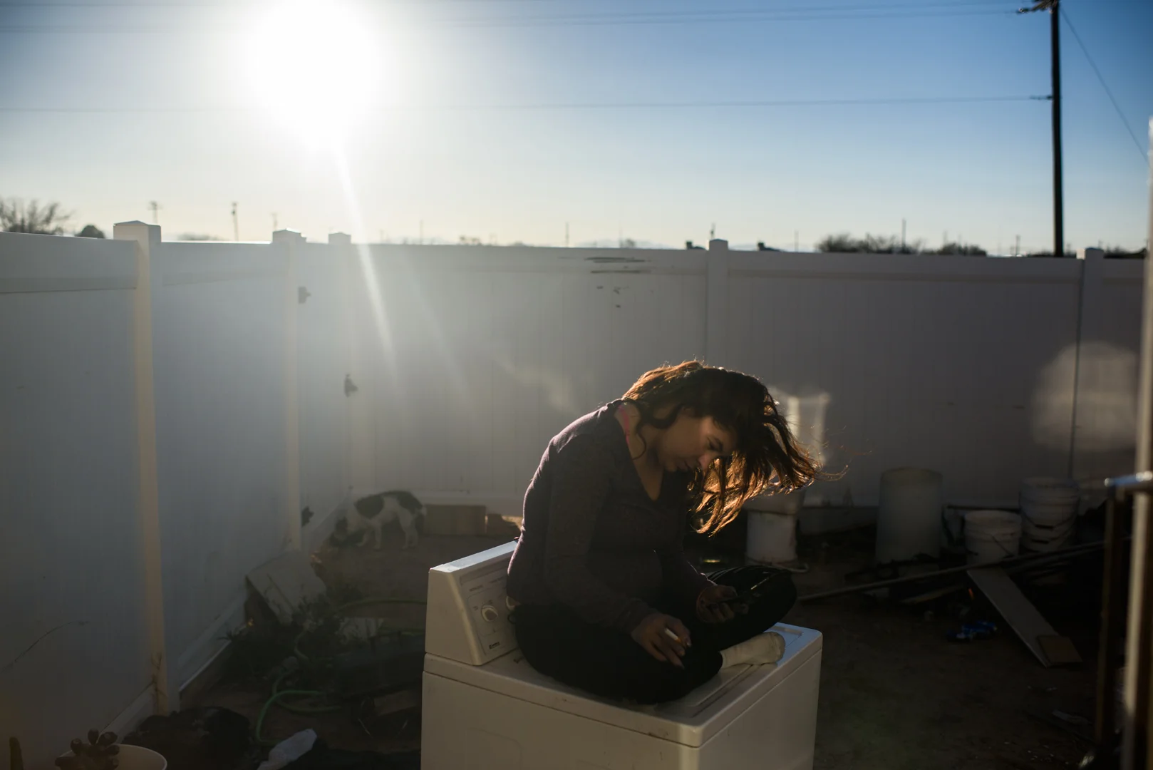 Delilah sits on a dryer in Alex’s mother’s yard. One day, Delilah decided to get sober. She fled Albuquerque with two people in an RV who had been previously homeless. They took her to a town in Southern New Mexico where she met Alex, age 23.