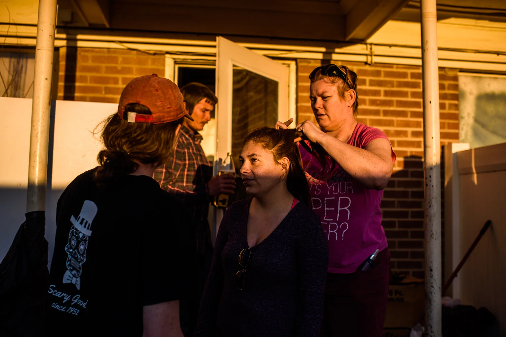 Delilah looks at Alex as Alex’s mother, Crystal, braids her hair and Charlie, Alex’s brother, stands in the door way.