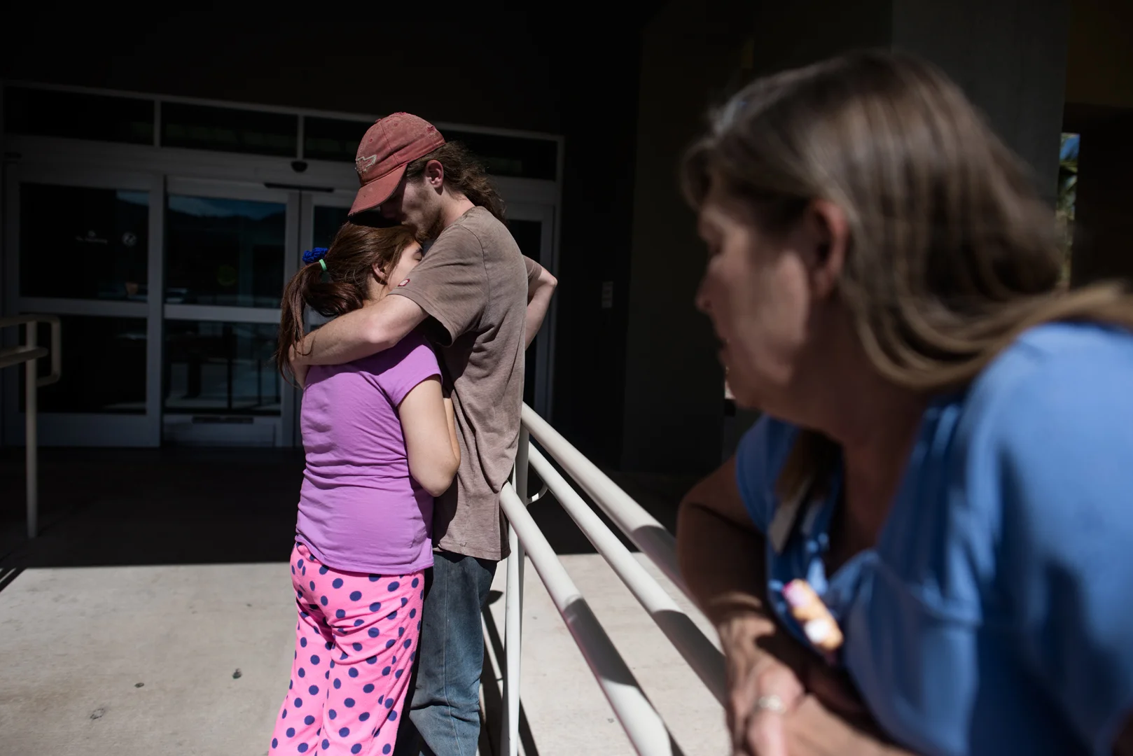 Alex kisses Delilah head after she is released from behavioral medicine, while a nurse stands beside them; Delilah stayed 7 days in the hospital after her suicide attempt.