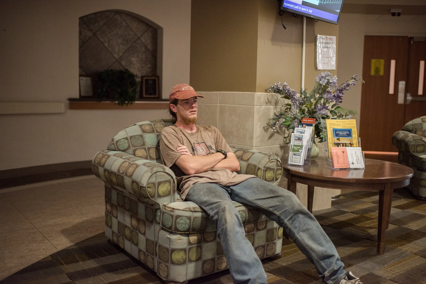 Alex sits in a chair in the behavior medicine, mental ward, area of the hospital before visiting Delilah.