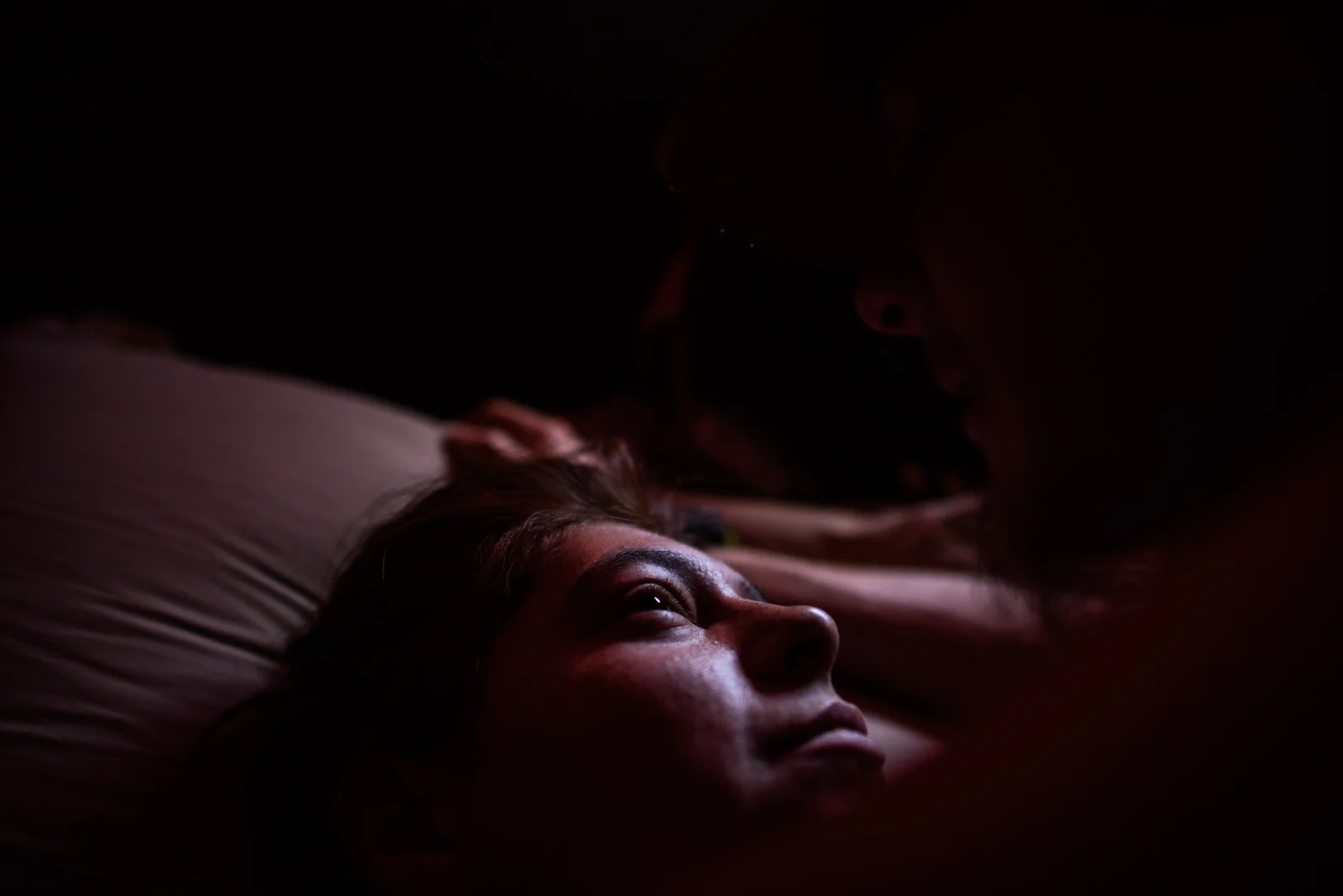 Delilah lies down and looks at Alex.