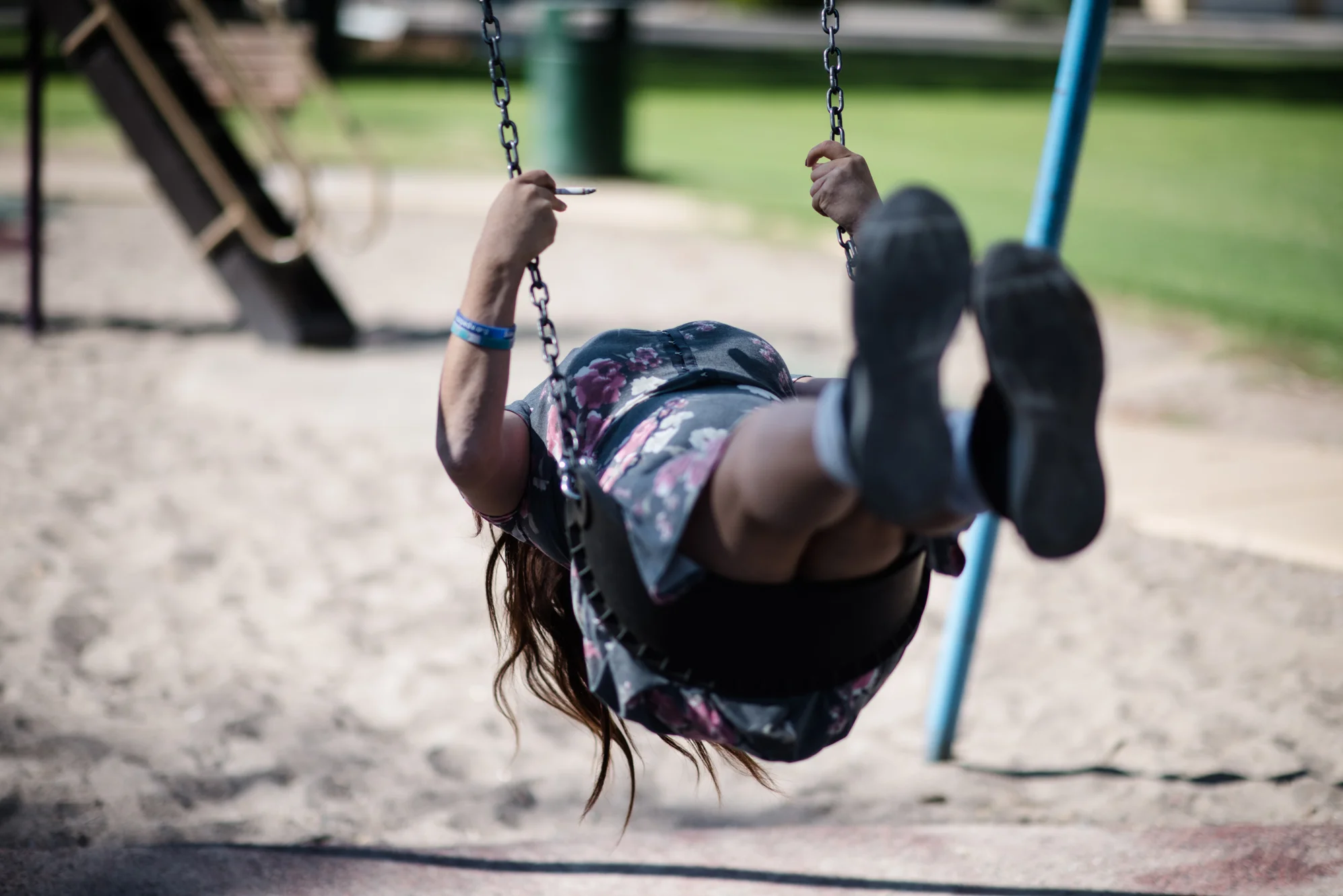 Delilah leans back while sitting on a swing.