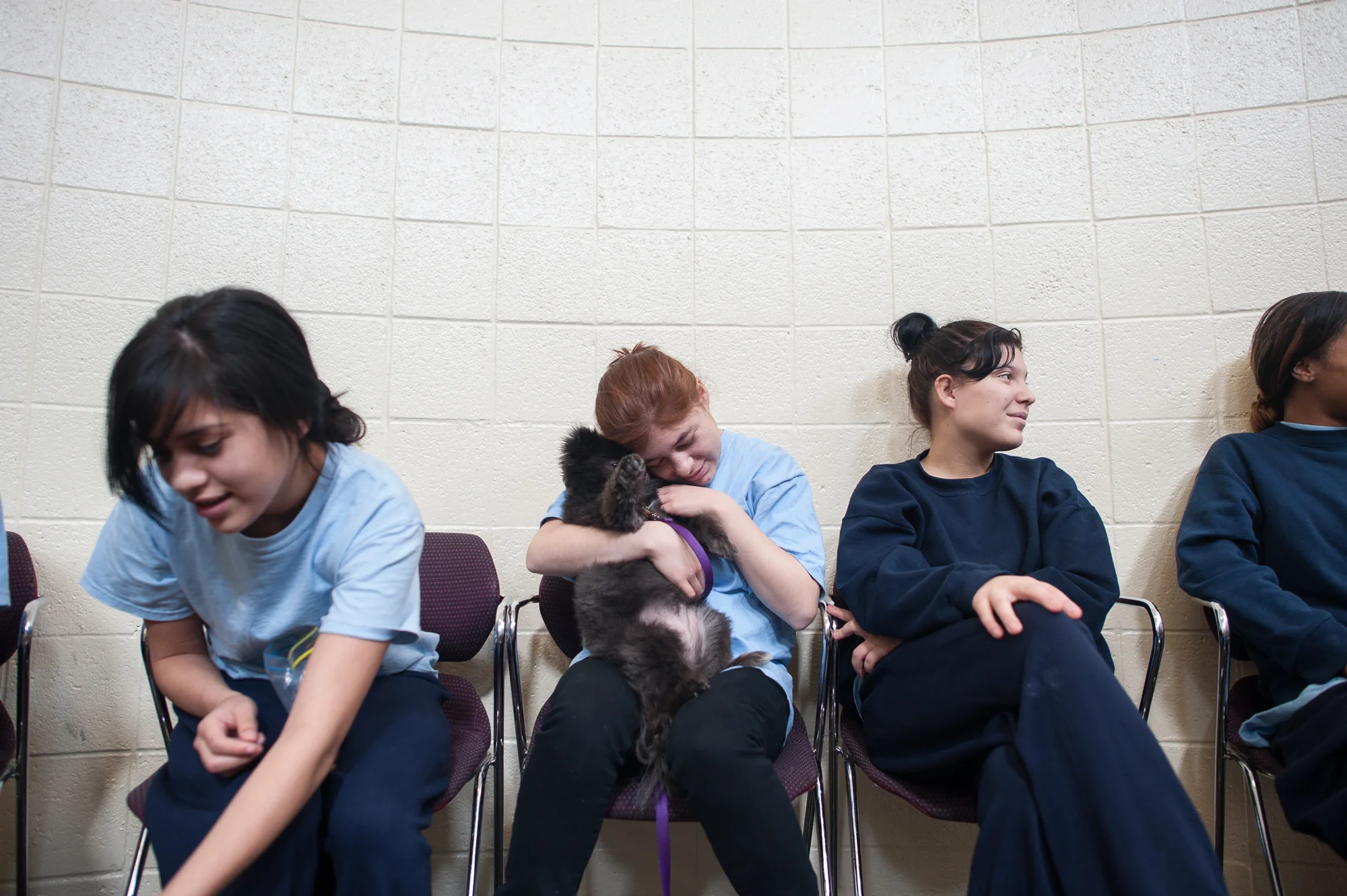 Sitting amongst girls, Delilah holds a dog during a pet therapy session at the juvenile detention center.