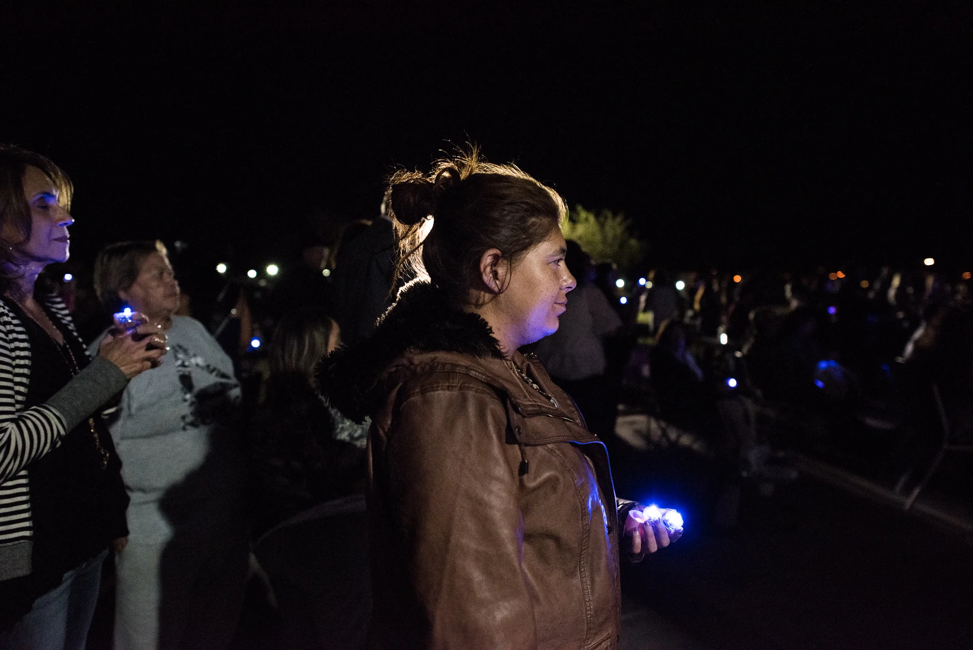 Delilah holds candles during a vigil at a Domestic Violence Awareness event where survivors shared their stories on stage.