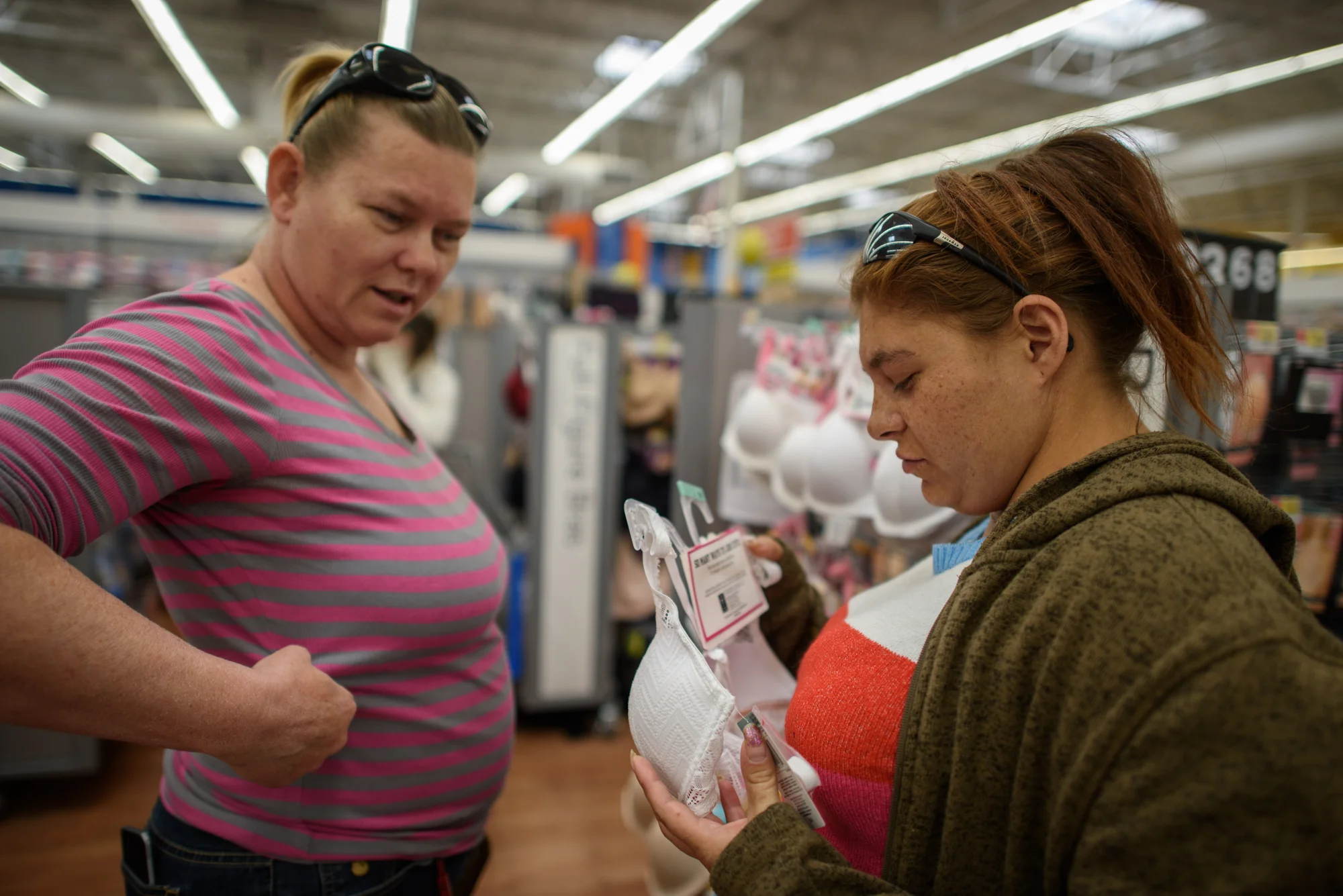 Crystal shows Delilah how a bra should fit, as Delilah looks at bras at Walmart.