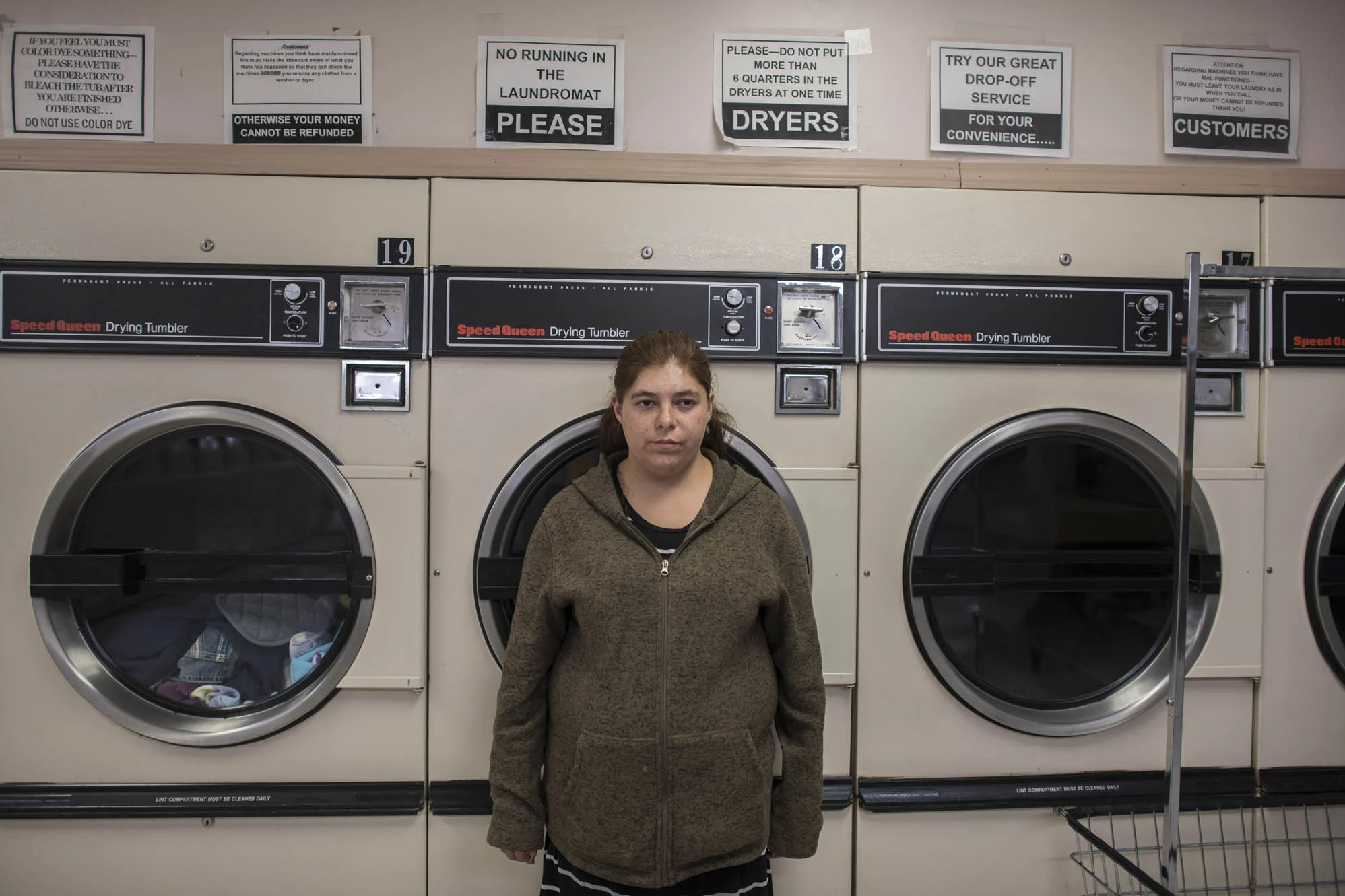 Delilah leans against a washer at a laundromat.