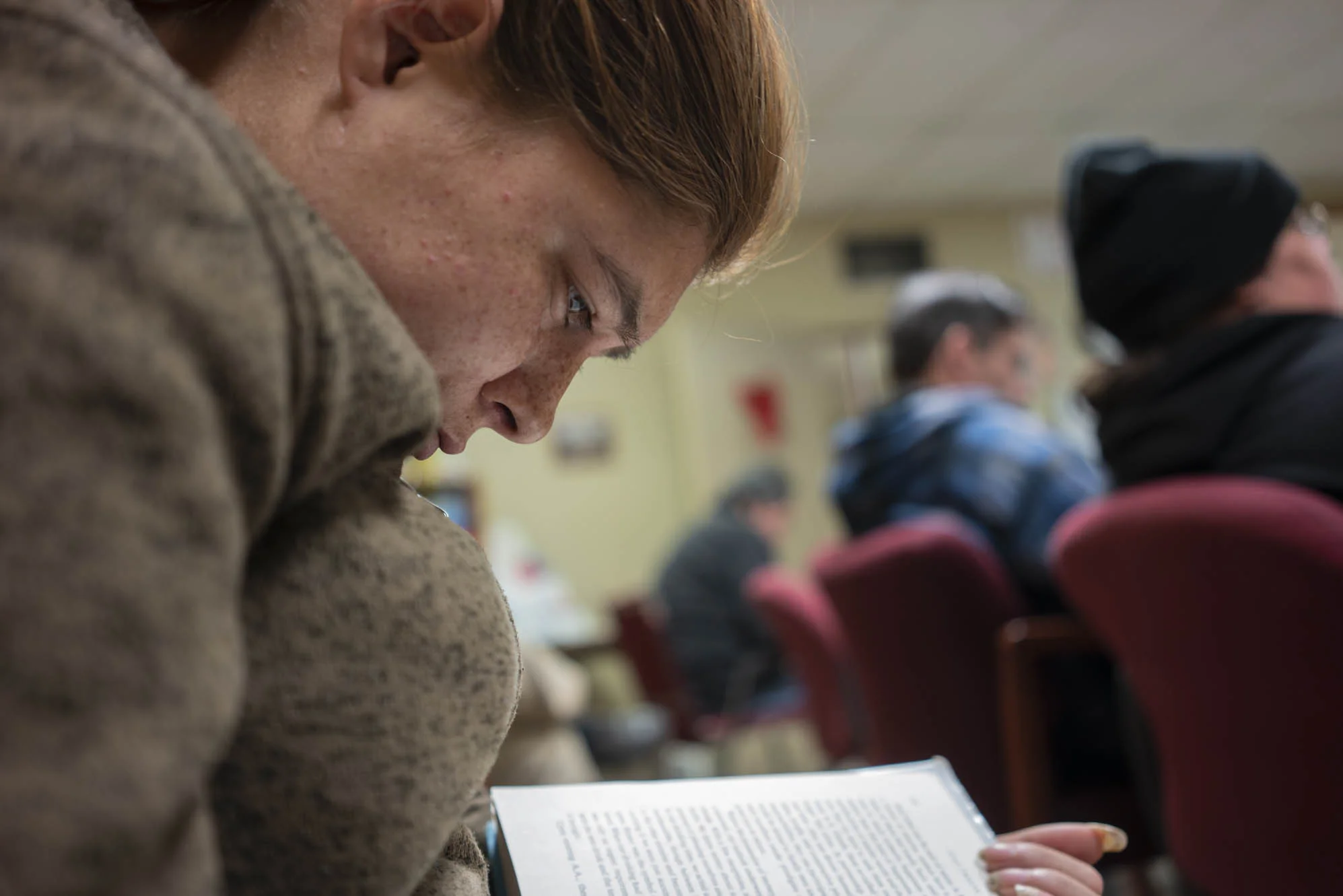Delilah reads from the Big Book during an AA meeting.