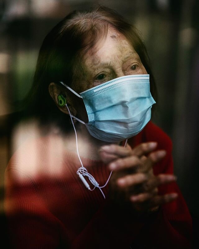 Fabiola Toralba, 95, looks at her daughters, Cecilia, Gemma and Marifa and grandson, Anthony, as they stand in front of a glass door at the Alexandria Care Center on May 10. Fabiola listens to Gemma read The Lord's Prayer through Facebook messenger. 