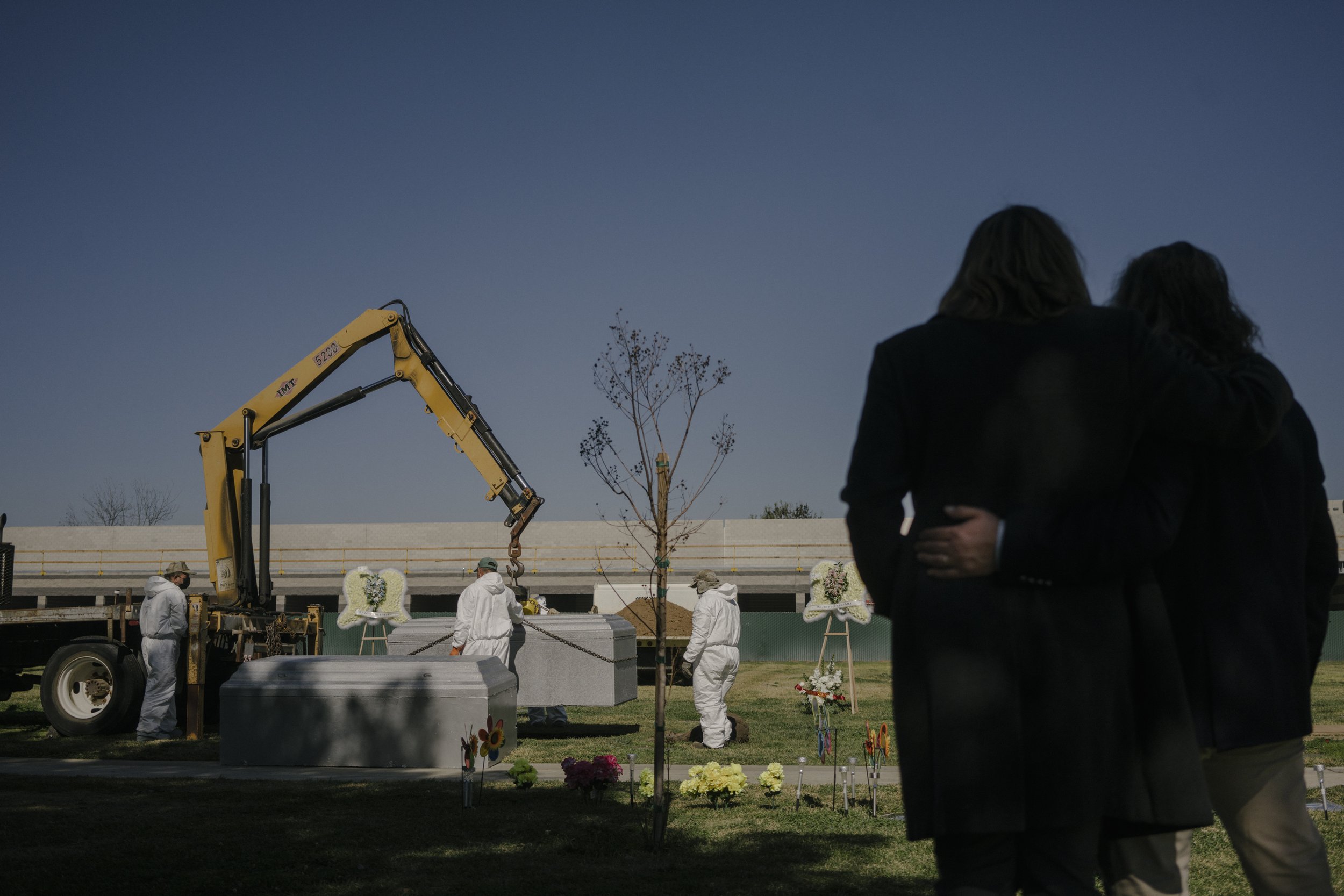  Family members of Maria Serrano and her son, Victor Serrano, embrace as they watch the burial of their coffins at Park Lawn Cemetery in Los Angeles, California. Both Maria and Victor passed away from COVID-19 related complications in January 2021.  