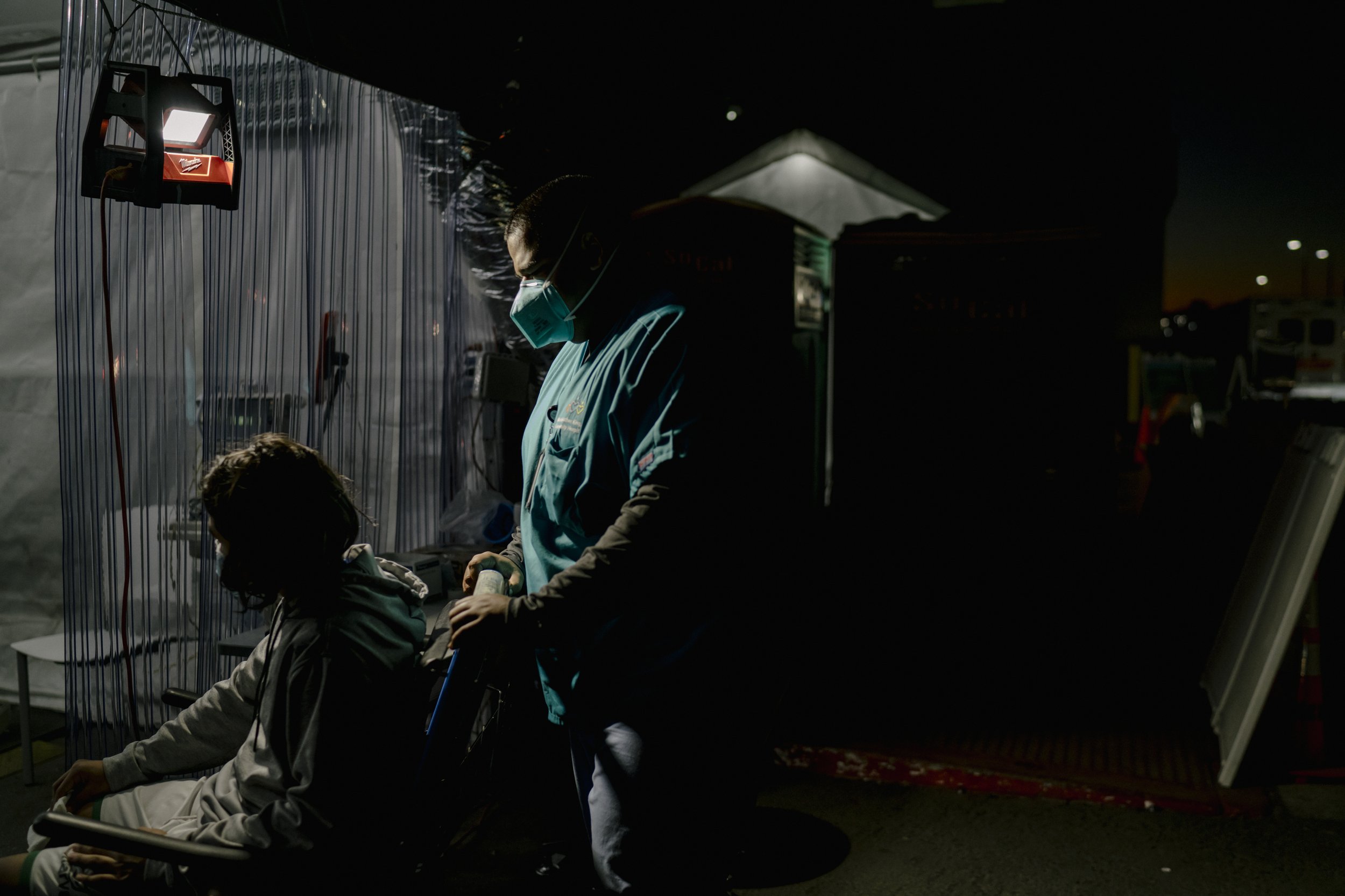  A healthcare worker pushes a patient into a triage tent outside the Emergency Department. 