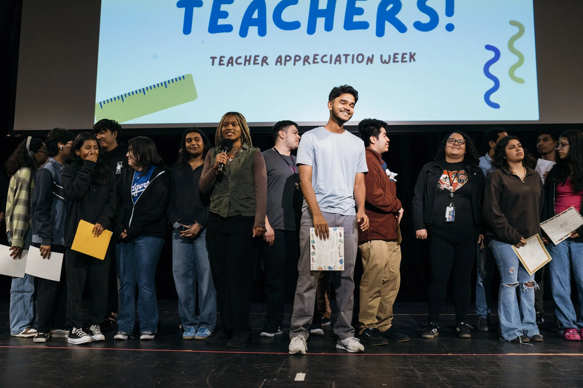  Sujana and Kaelin stand on stage with students and teachers for Teacher Appreciation during an assembly in the former Cocoanut Grove Nightclub that is now an auditorium. 