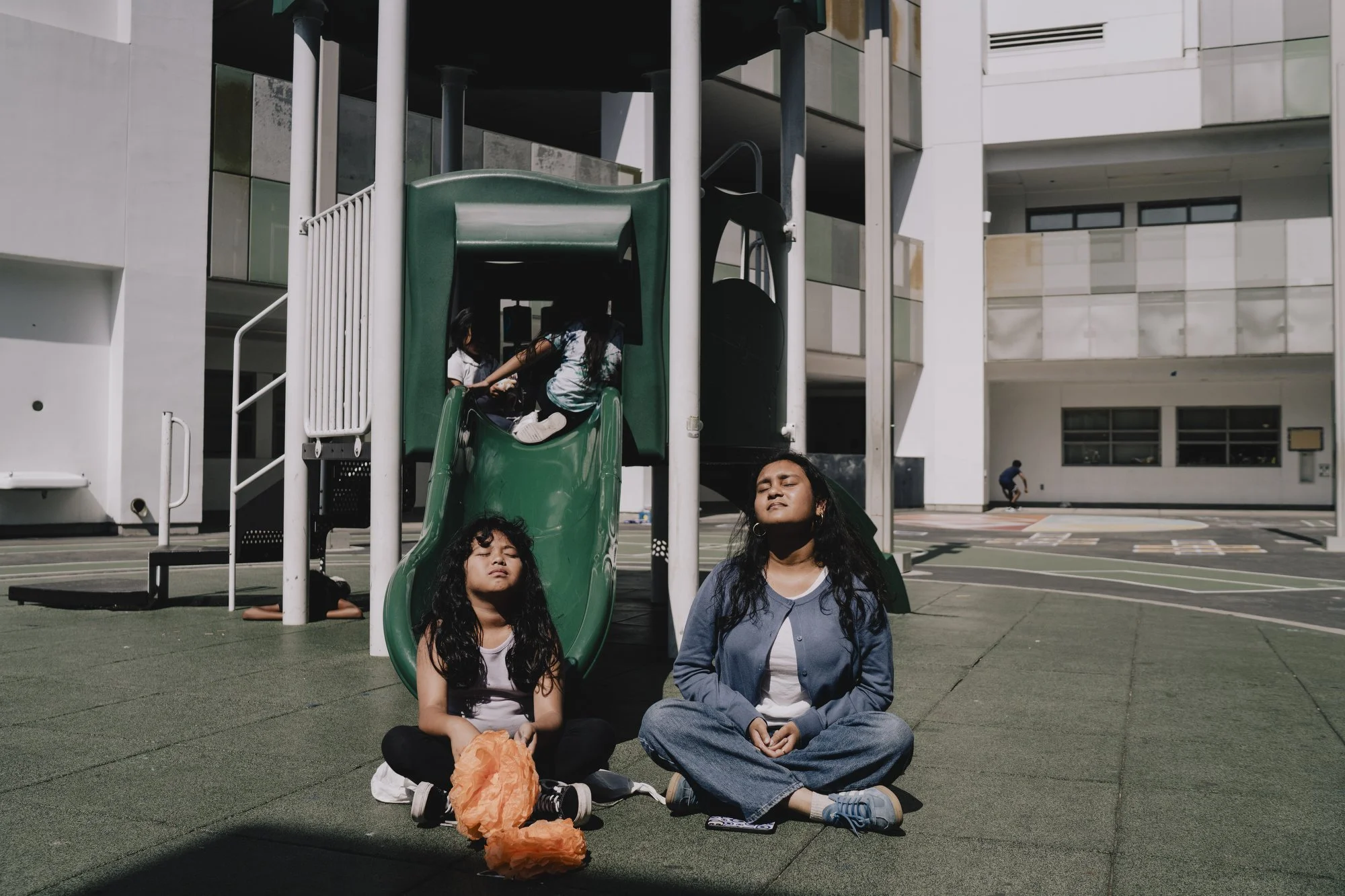  Sujana, a student in the 11th grade, who works as a teacher’s assistant in the afterschool program, sits and takes in the sun with 2nd grade student, Galilee, in the yard at the UCLA Community School in Los Angeles, California.  “Kind of the biggest