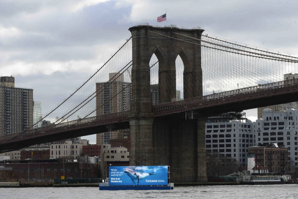 A 60-foot-wide advertising barge with a 20-foot high screen, roaming the East River and New York Harbor, has created an uproar from residents and politicians. Eagle photos by Todd Maisel.