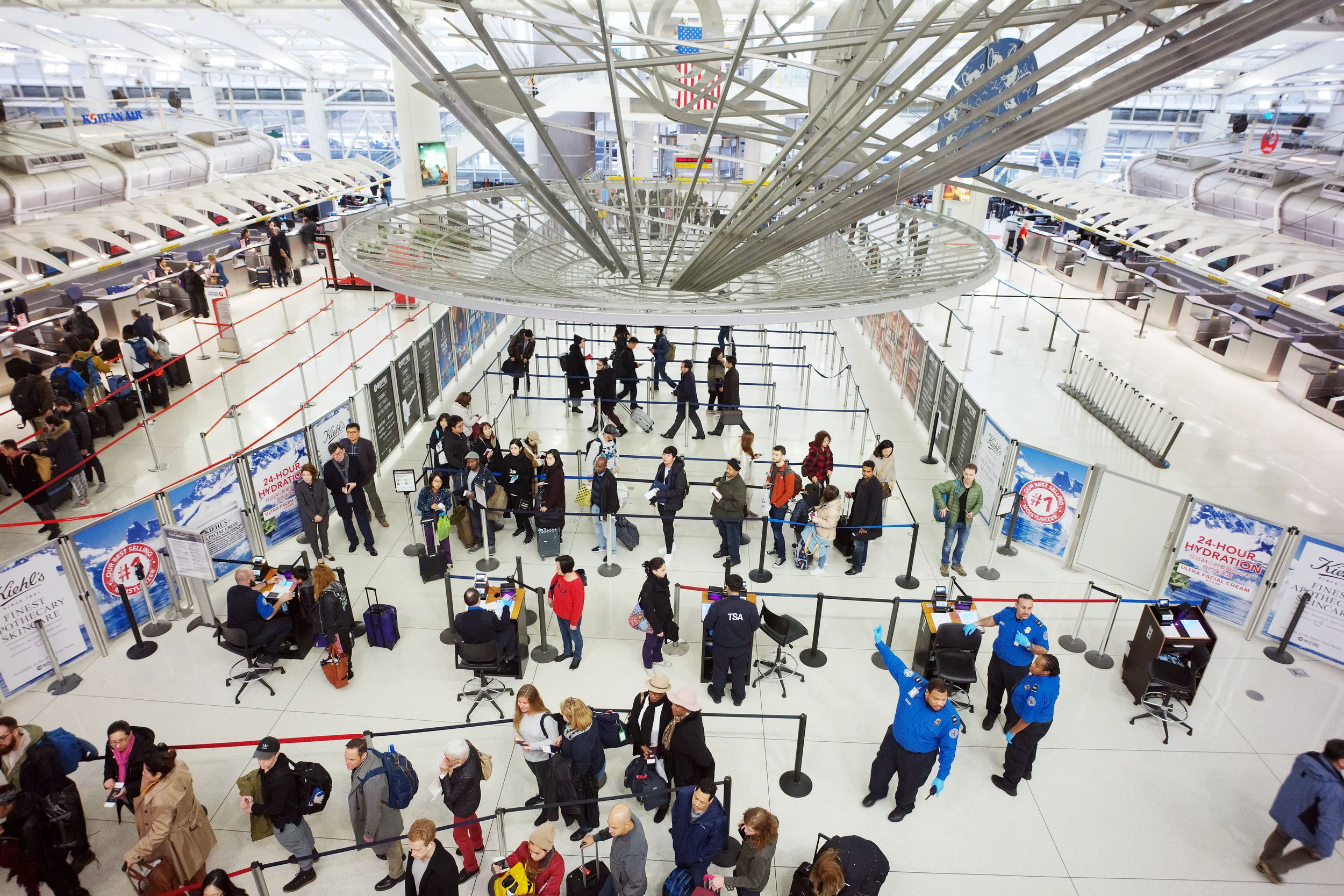 Passengers stand in line as they wait to pass through a TSA security checkpoint at JFK International Airport