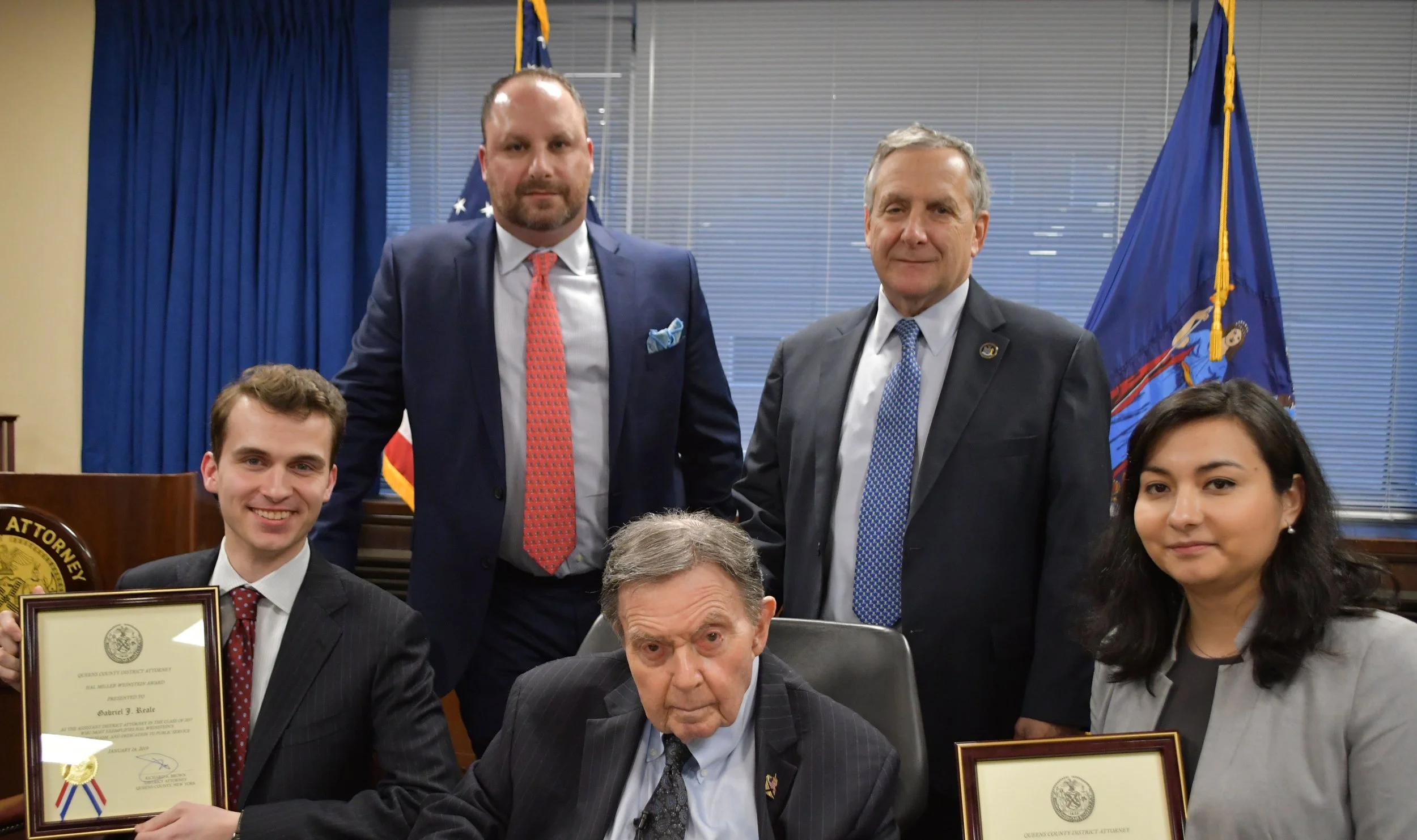 Queens District Attorney Richard A. Brown (front, center) named Assistant District Attorneys Gabriel Reale (front, left) and Chrystina Lopera (front, right) as the recipients of the 28th Annual Hal Miller Weinstein Memorial Award. Joining Brown in presenting the awards were (back left to right) Weinstein’s brother, Lloyd, an attorney and Weinstein’s uncle, Queens Supreme Court Justice Jeremy S. Weinstein. Photo courtesy of the Queens District Attorney’s Office.