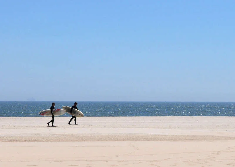 Surfers walk along Rockaway Beach. Photo via NYC Parks.