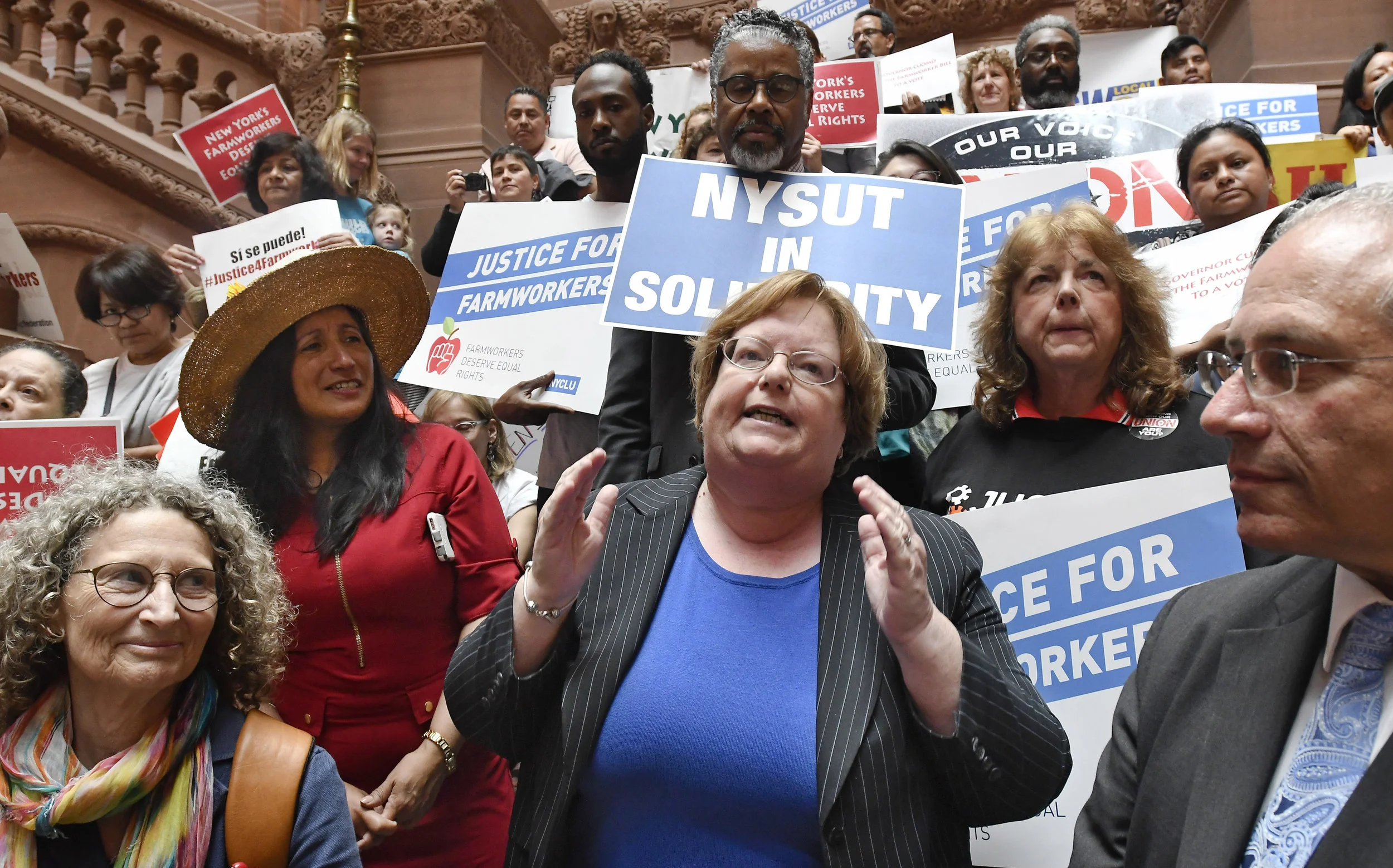 Assemblymember Catherine Nolan (center) addresses a coalition of farmworkers’ rights advocates in Albany in 2018. AP Photo/Hans Pennink.