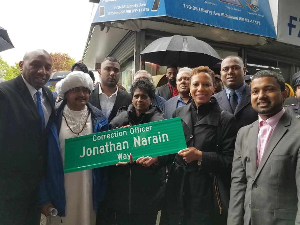 Late CO Jonathan Narain’s family holds the sign renaming a Richmond Hill intersection. Councilmembers Donovan Richards (left) and Adrienne Adams (third from right) and District Leader Richard David (right) attended the event earlier this month. Photos courtesy of Richard David.