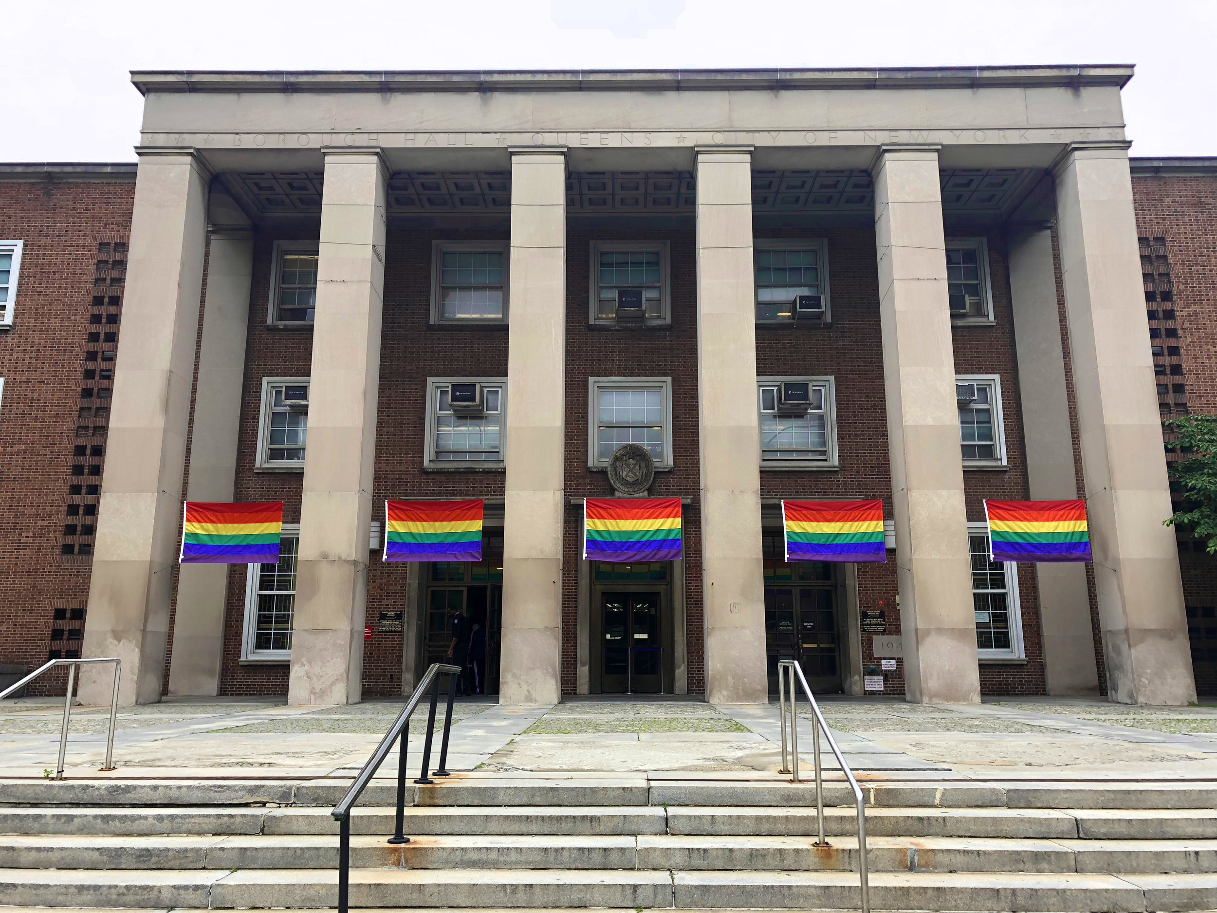 Pride flags fly in front of Queens Borough Hall in Kew Gardens. Photo courtesy of Queens Borough Hall.