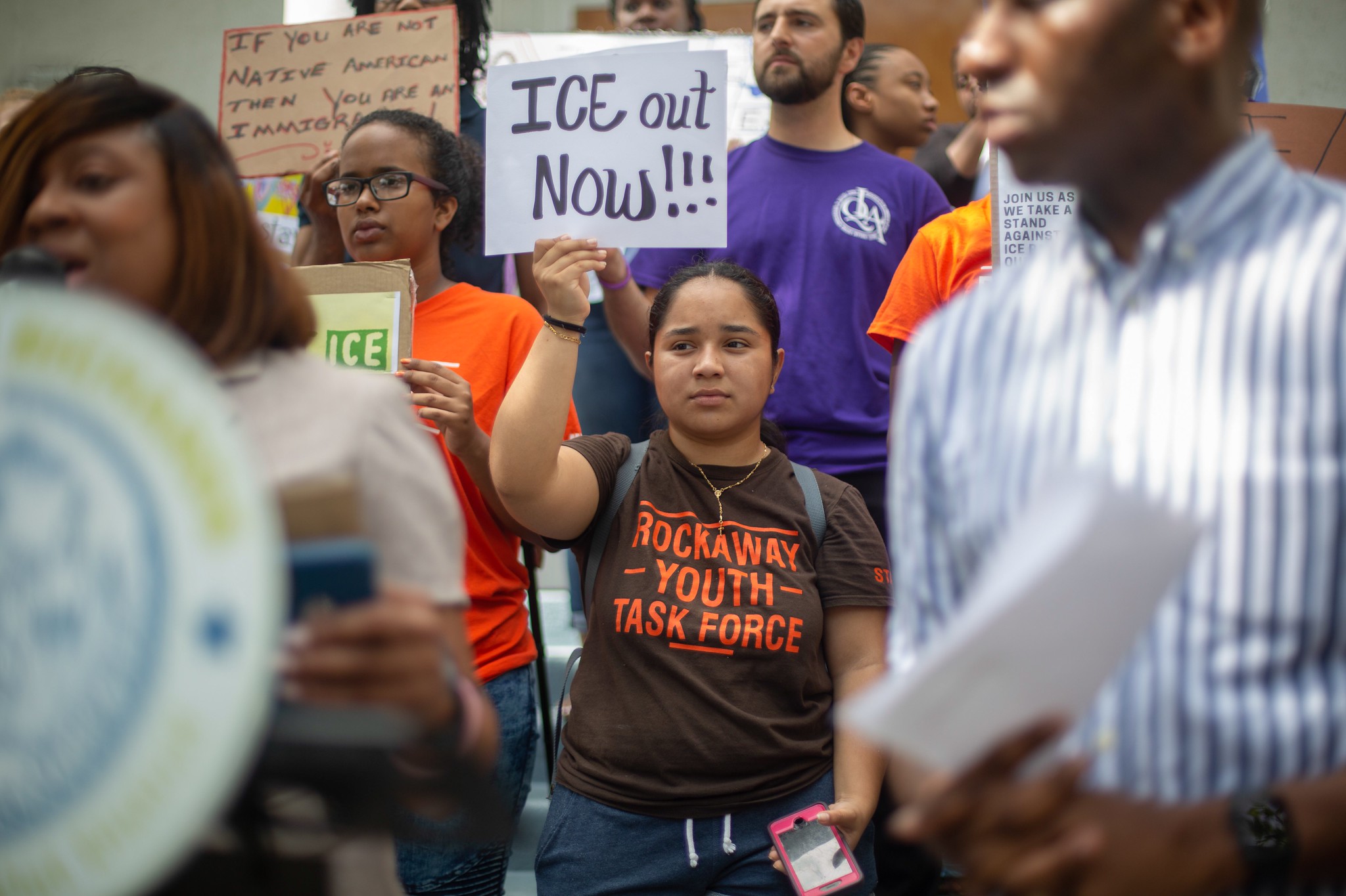 Rockaway Youth Task Force organizer Andrea Colon holds a sign denouncing immigration raids at a rally in Far Rockaway last week. Eagle photo by Rachel Vick.
