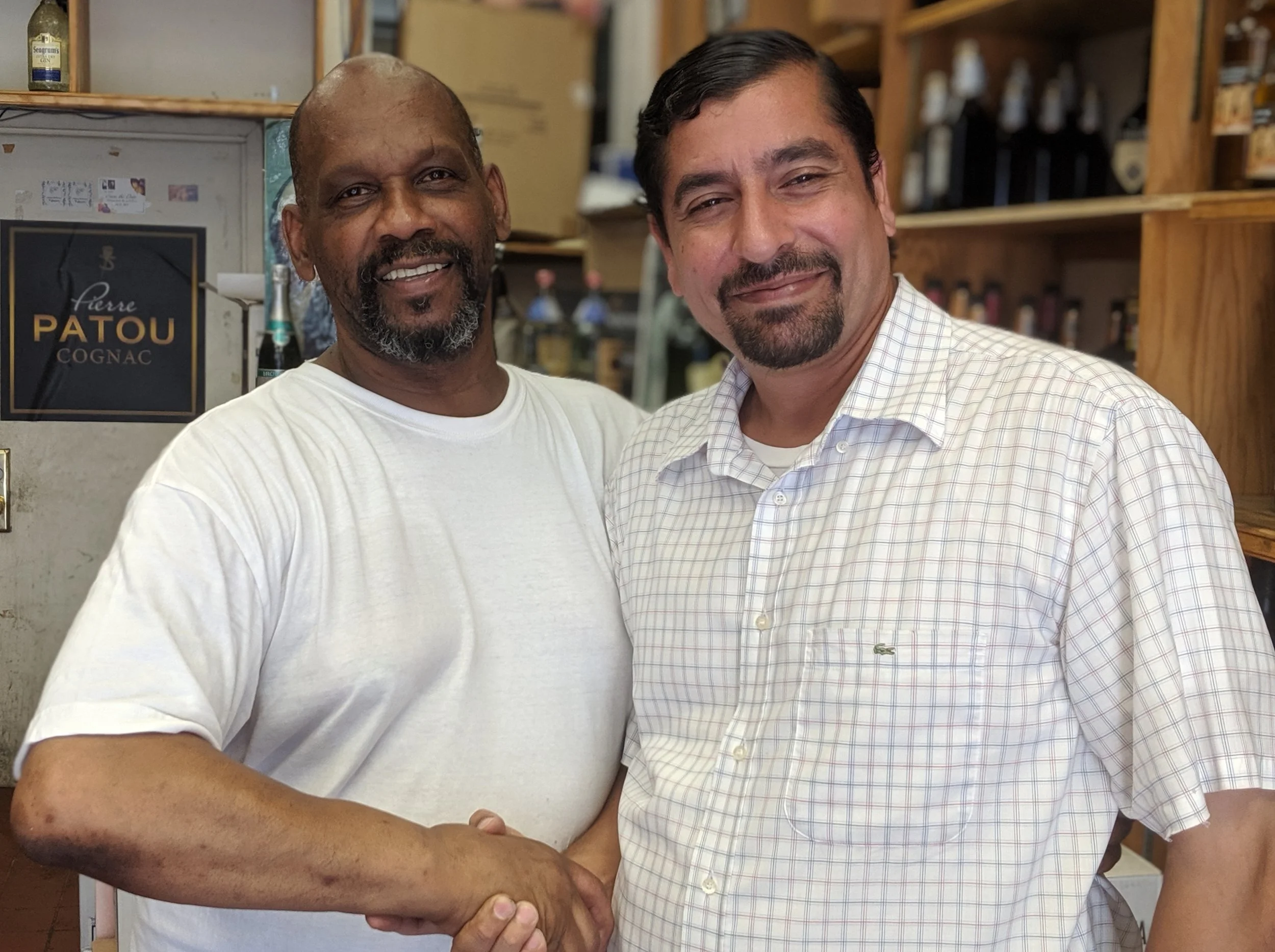 Martinez shakes hands with Tony Robinson, who owns a local liquor store. Tenant leaders used to gather for meetings at Robinson’s shop, he said. Eagle file photo by Phineas Rueckert.