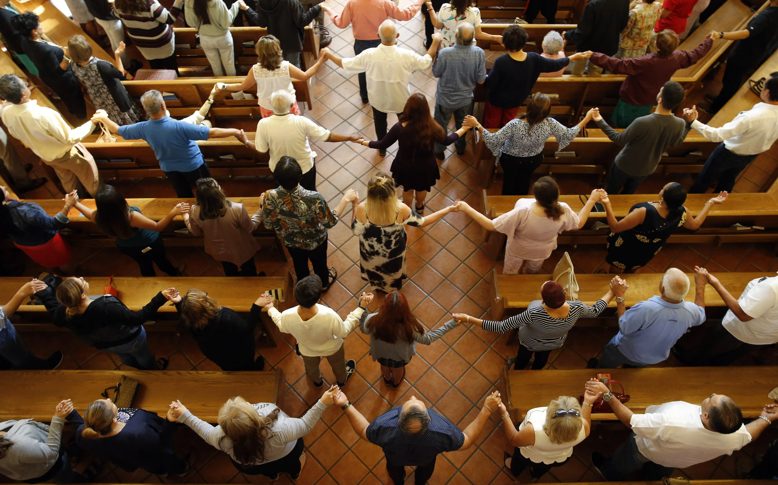 Churchgoers hold hands as they sing during a morning service at St. Pius X Church in El Paso, Texas on Sunday, a day after a white nationalist shot and killed more than 20 people. Vernon Bryant/The Dallas Morning News via AP.