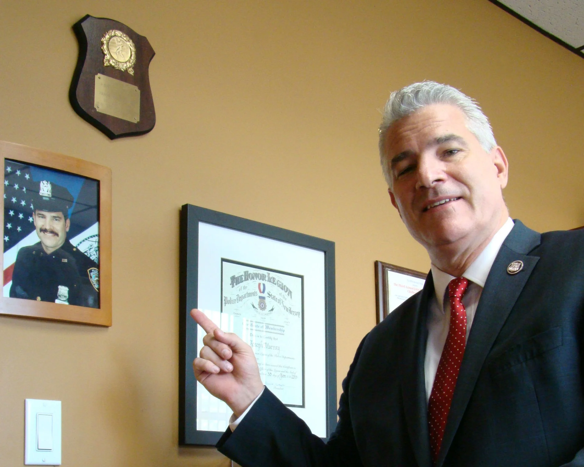 Murray, a former NYPD officer in the 115th Precinct, points to a photo of himself in police uniform. Photo courtesy of Murray.