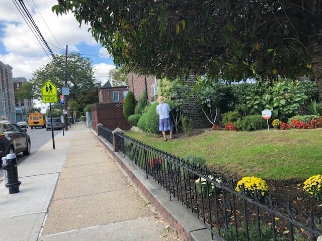 A Ditmars Boulevard resident tends to her lawn.