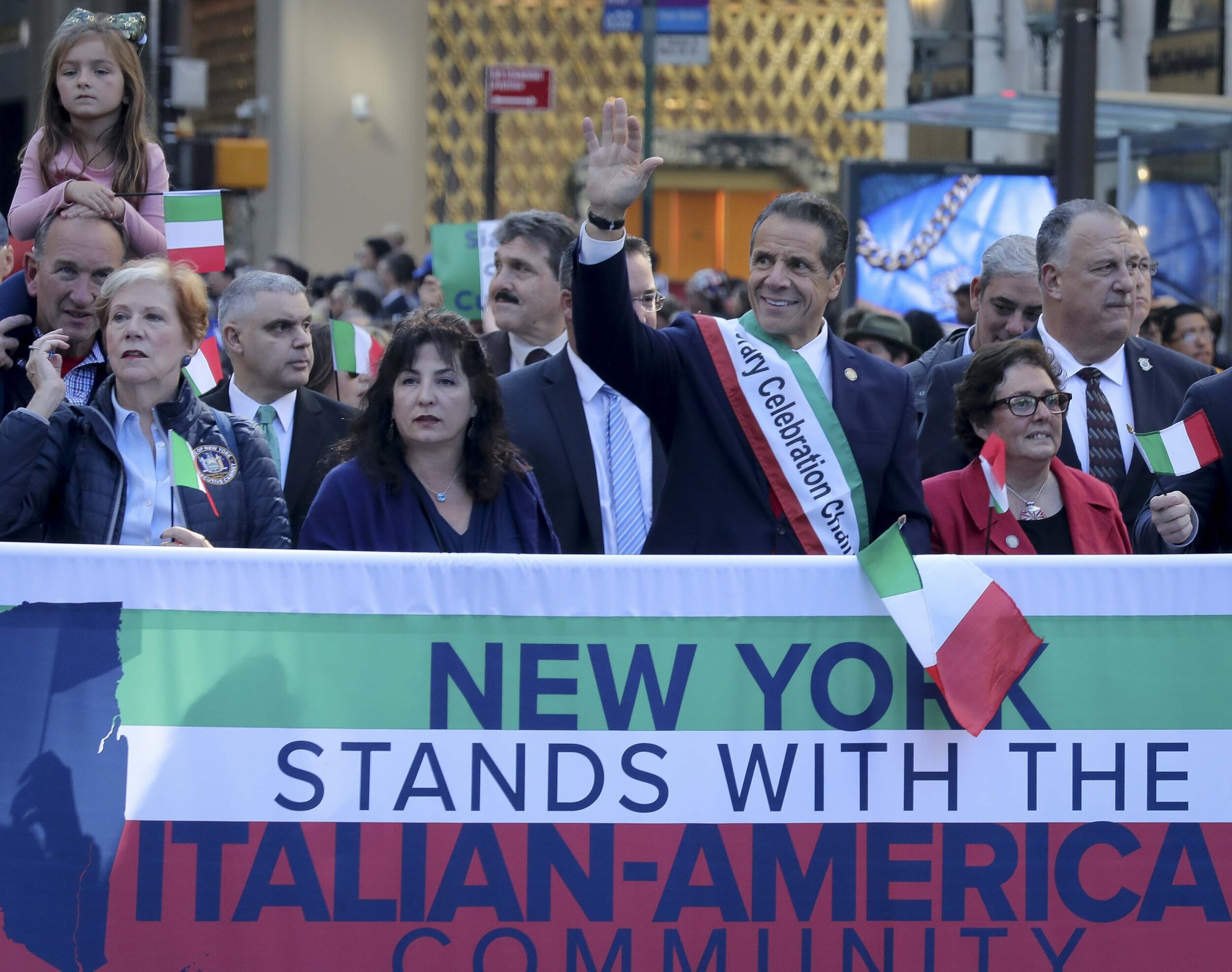 Gov. Andrew Cuomo, center, waves as he marches behind a banner with an entourage, during the Columbus Day Parade in Manhattan. Cuomo announced the same day that he would be establishing a state-led commision to construct a Cabrini statue. AP Photo/Bebeto Matthews.