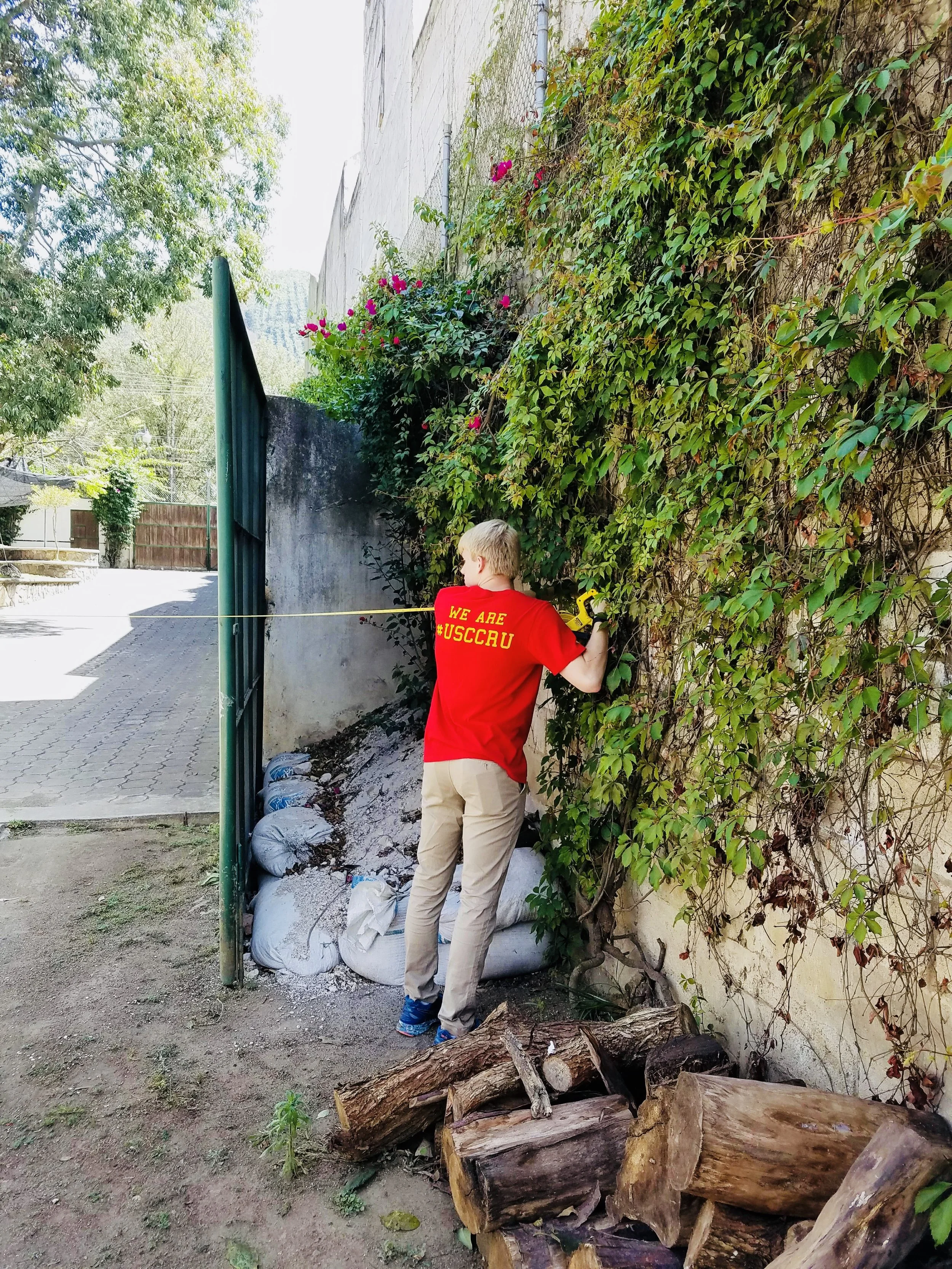 Taking measurements for the rain water collection system on the Common Hope campus during the 2018 assessment trip.