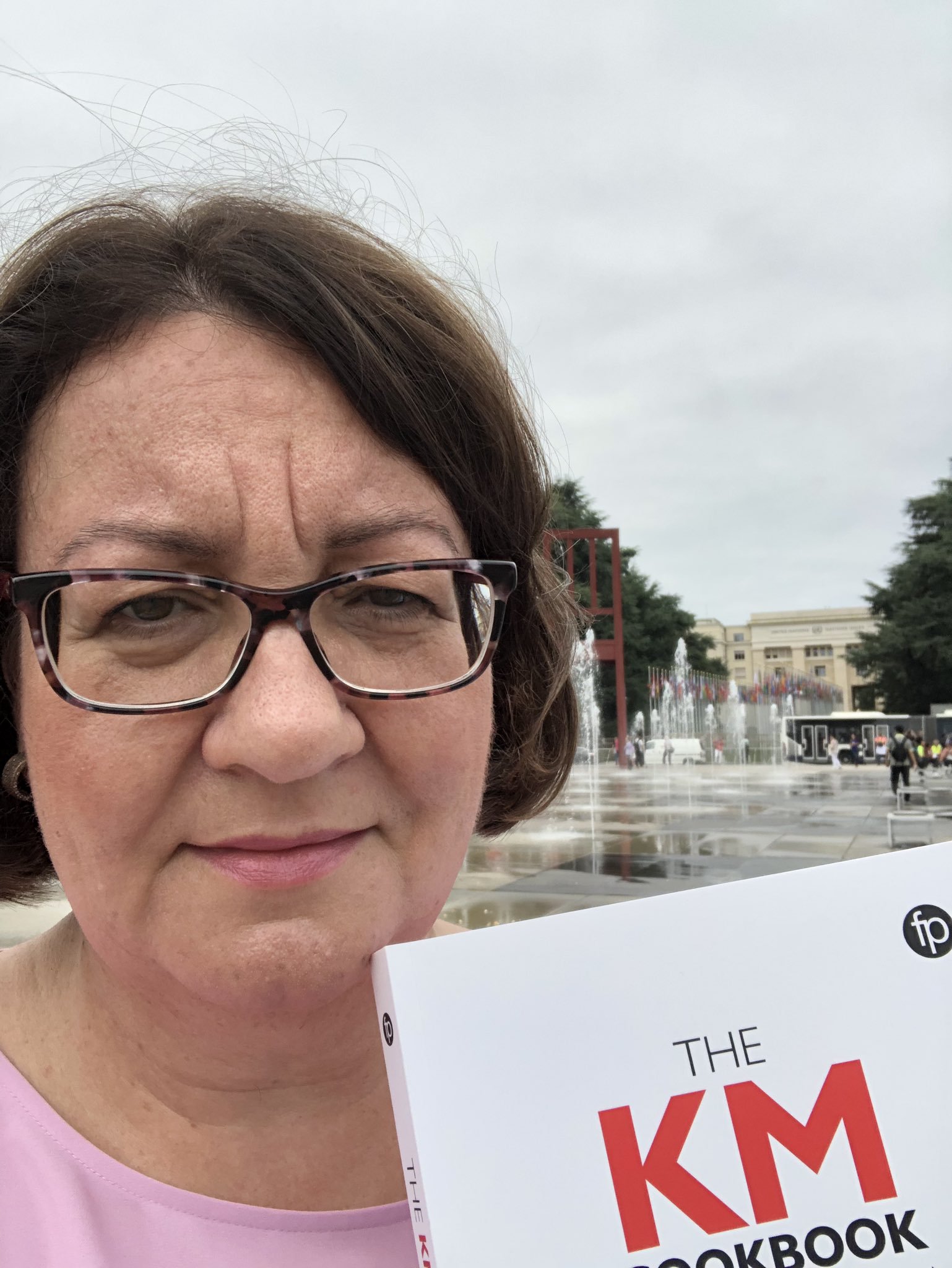 Denise Carter with her copy of the KM Cookbook in Geneva