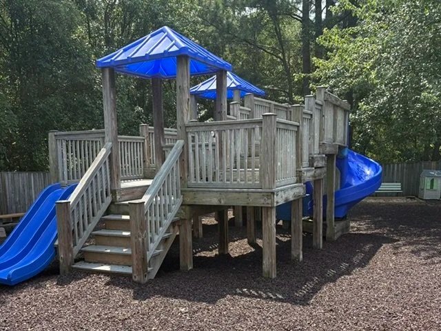 Large playground structure with multiple slides surrounded by mulch