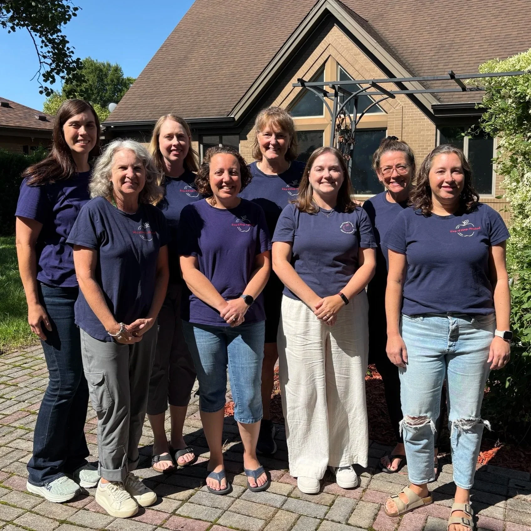 Picture of the 8 female staff members of King of Kings Preschool outside of the church